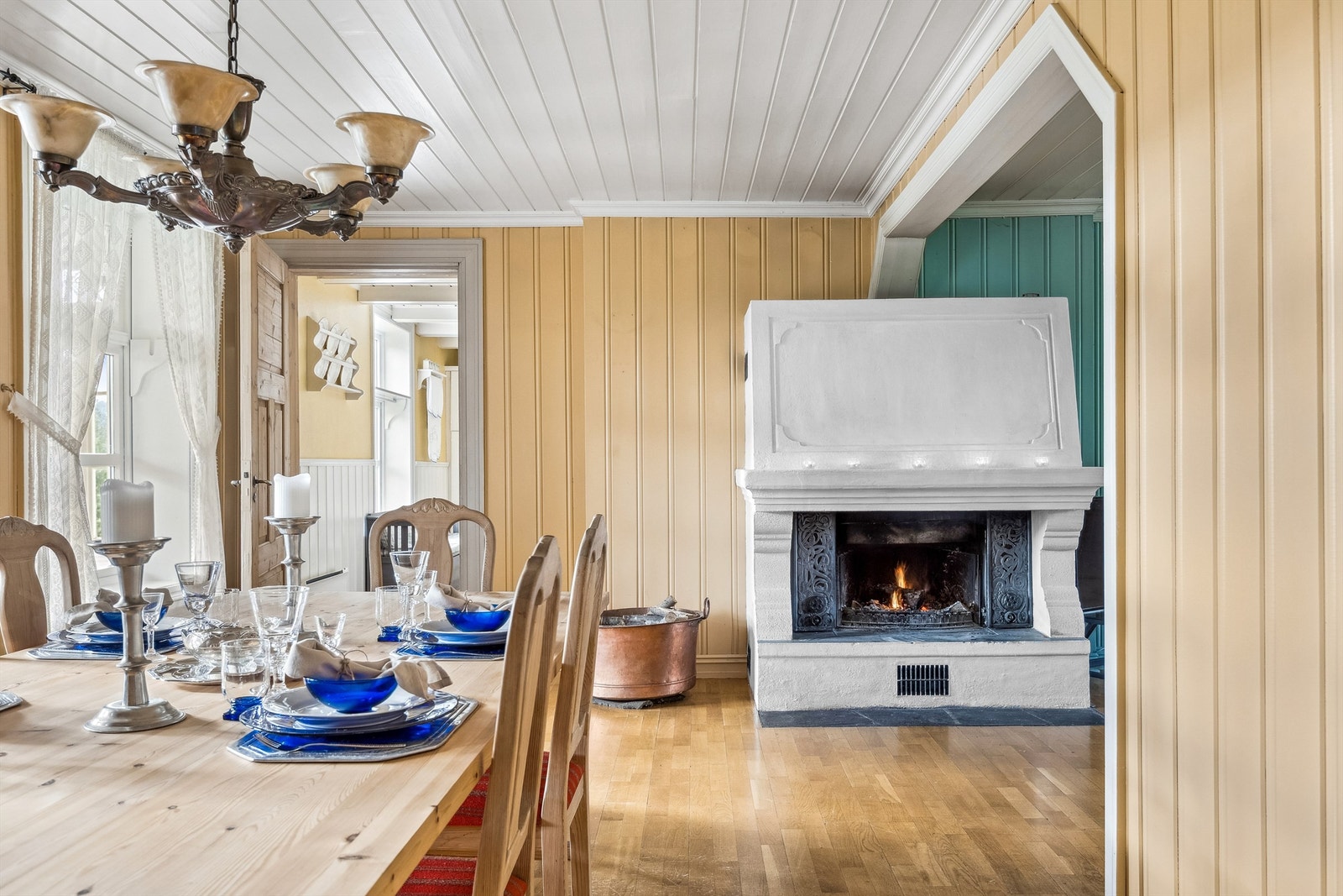 Koselig spisestue med peis, lyse farger og store vinduer som gir rikelig med naturlig lys. Perfekt for hyggelige familiemåltider. Galleribilde