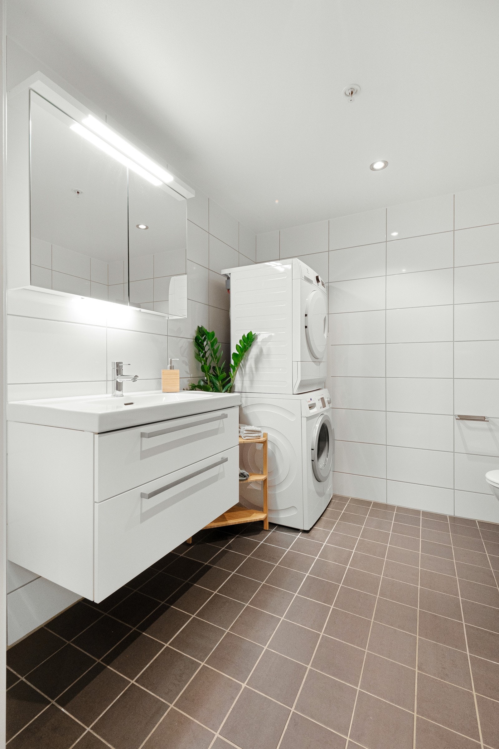 Badet er innredet med stor servantinnredning, speilskap med belysning, vegghengt toalett og dusjhjørne. Galleribilde