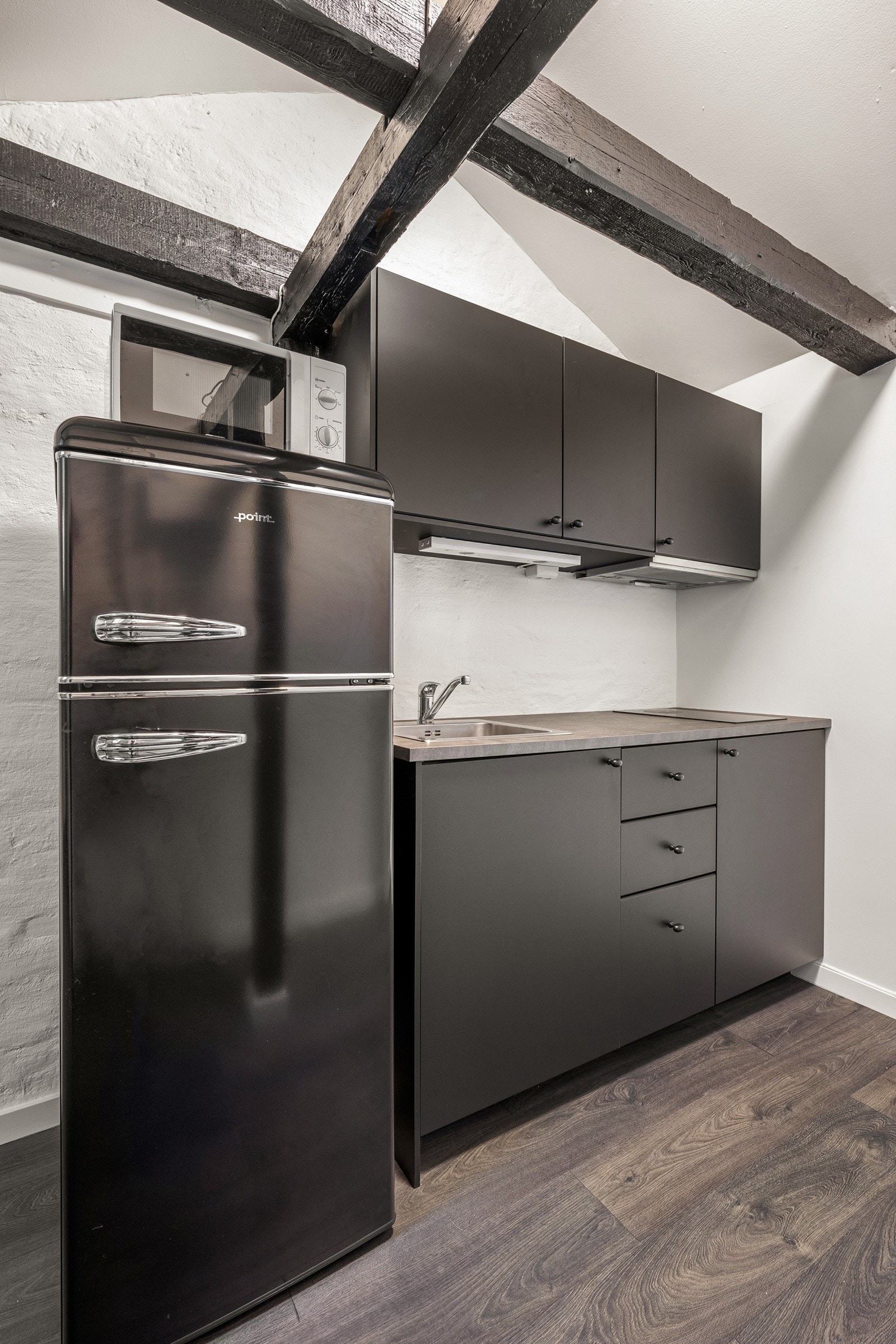 Kjøkkeninnredningen fremstår som stilrent med mørk innredning med slette fronter og laminat benkeplate. Galleribilde