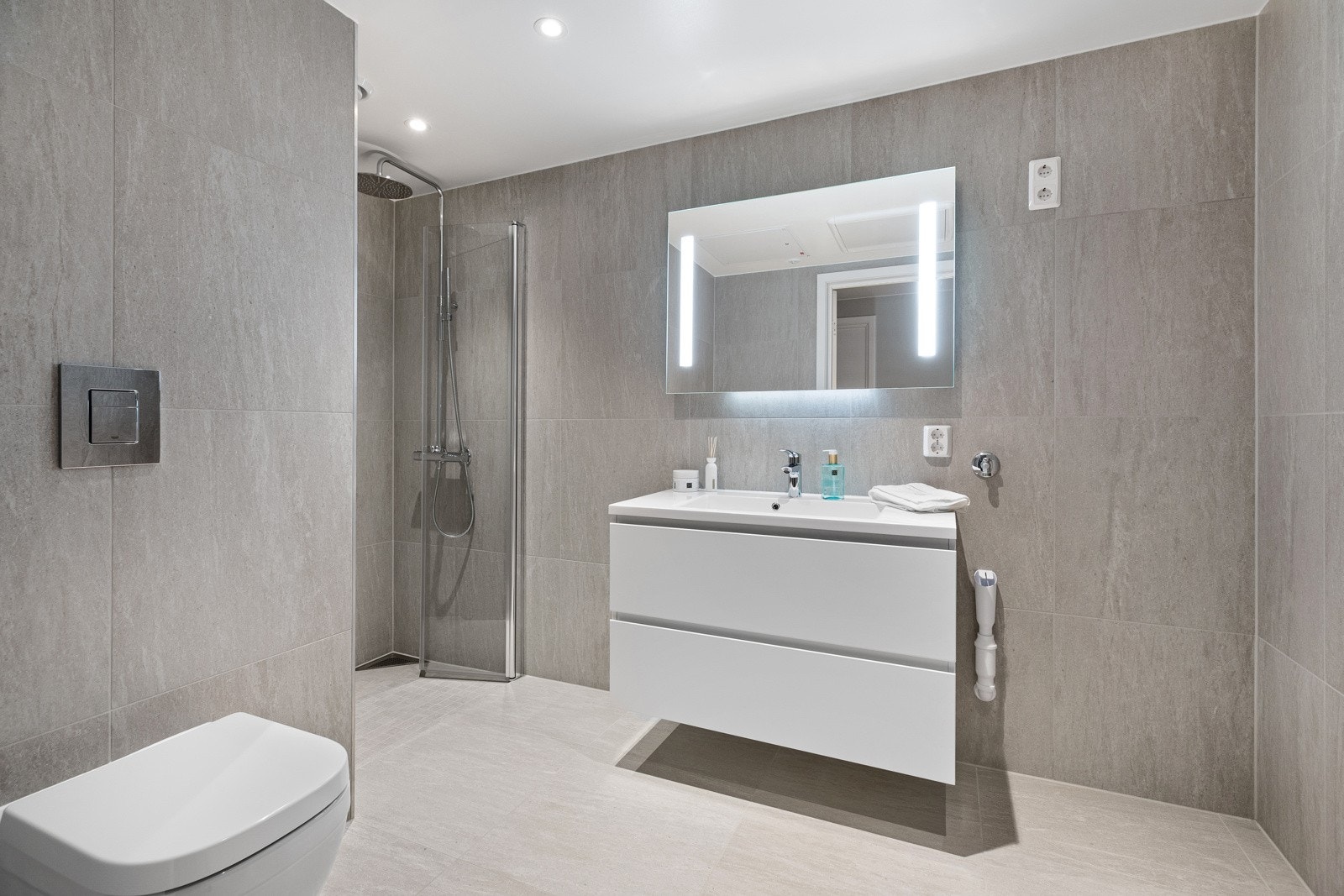 Det flislagte badet har downlights i tak, vannbåren gulvvarme og opplegg for vaskemaskin og tørketrommel. Galleribilde