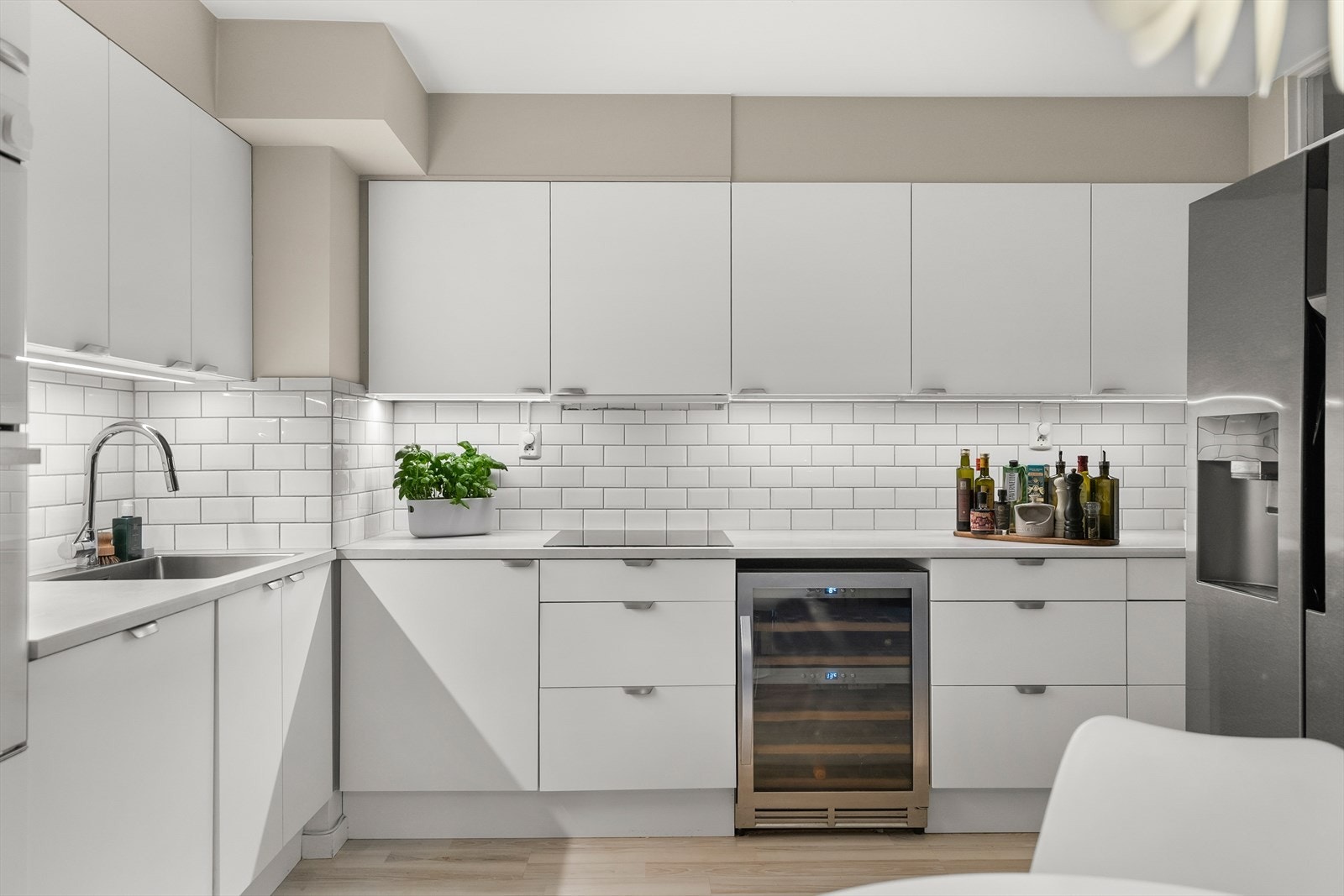 Fliser over kjøkkenbenk og benkebelysning. Det er Flexit kjøkkenventilator med avtrekk ut. Galleribilde