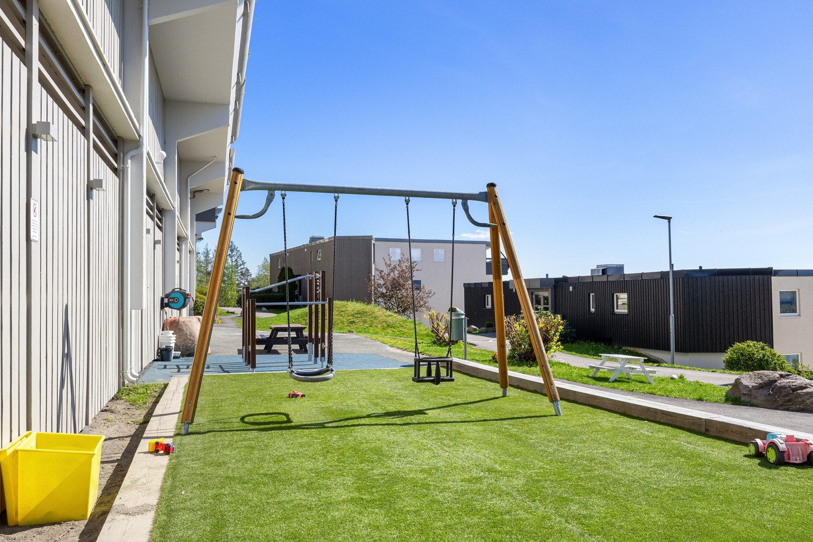 Rett utenfor husveggen er det en koselig lekeplass til barna. Felles utendørs sykkel og utstyrsbod for blokken Galleribilde