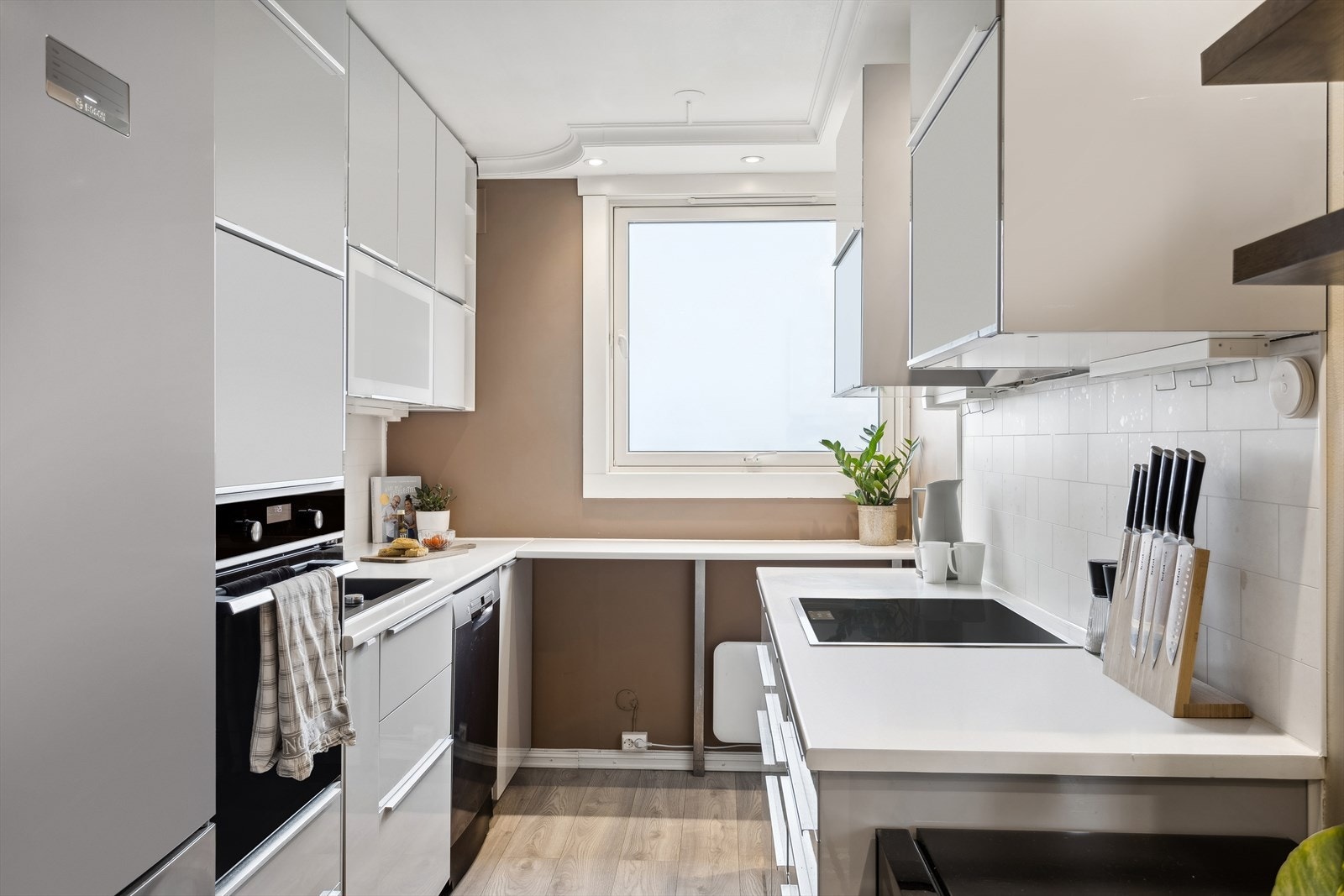 Delikat kjøkken med glatte høyglans fronter og vitrinedører med frostet glass samt laminat benkeplate med nedfelt kum i kompositt/plast. Blandebatteri med uttrekkbar kran. Galleribilde