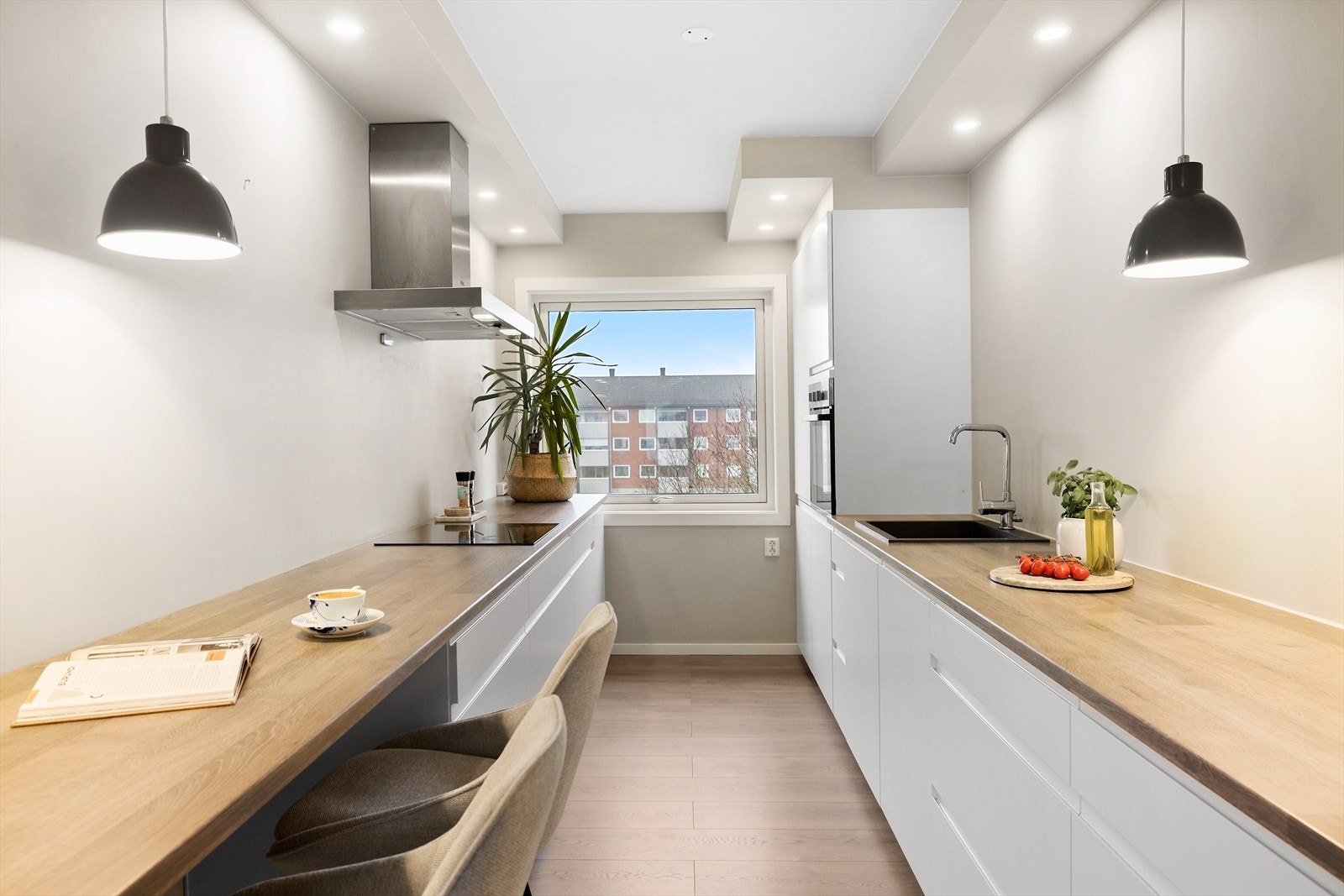 Pent kjøkken fra Kvik (2020) med slette og stilrene hvite fronter og laminert benkeplate Galleribilde