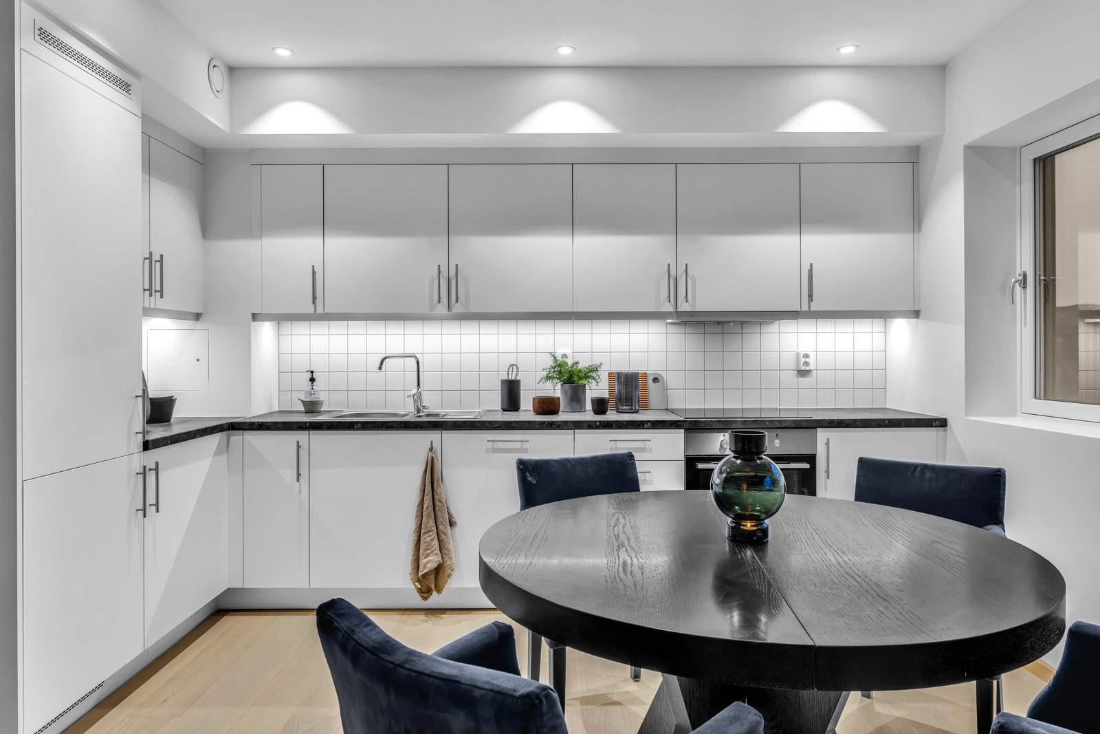 Kjøkkenet er utstyrt med moderne og elegante grå fronter og en rustfri stålkum som gir kjøkkenet et strømlinjeformet utseende samt fliser over benkeplate. Integrerte hvitevarer fra anerkjente leverandøren AEG. Galleribilde