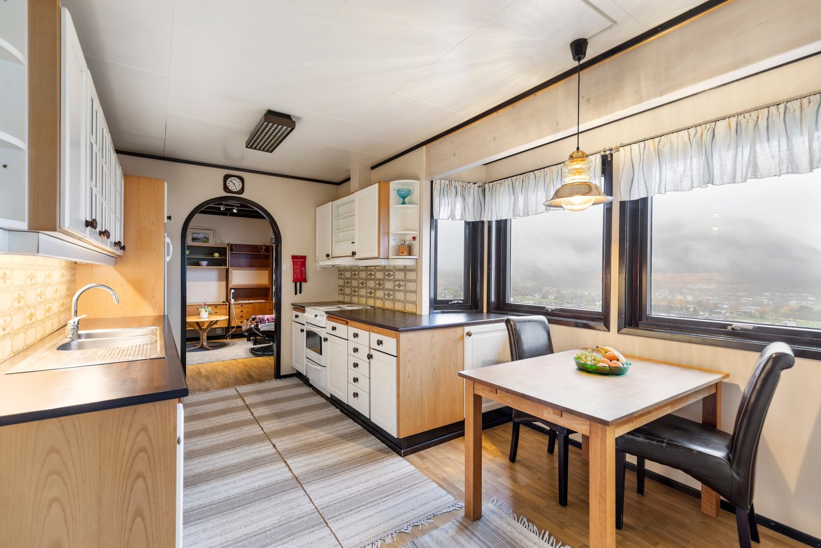 Kjøkkenet har innredning i hvite, profilerte fronter, laminat benkeplate med flis mot overskap, ventilator og opplegg for oppvaskmaskin. Galleribilde