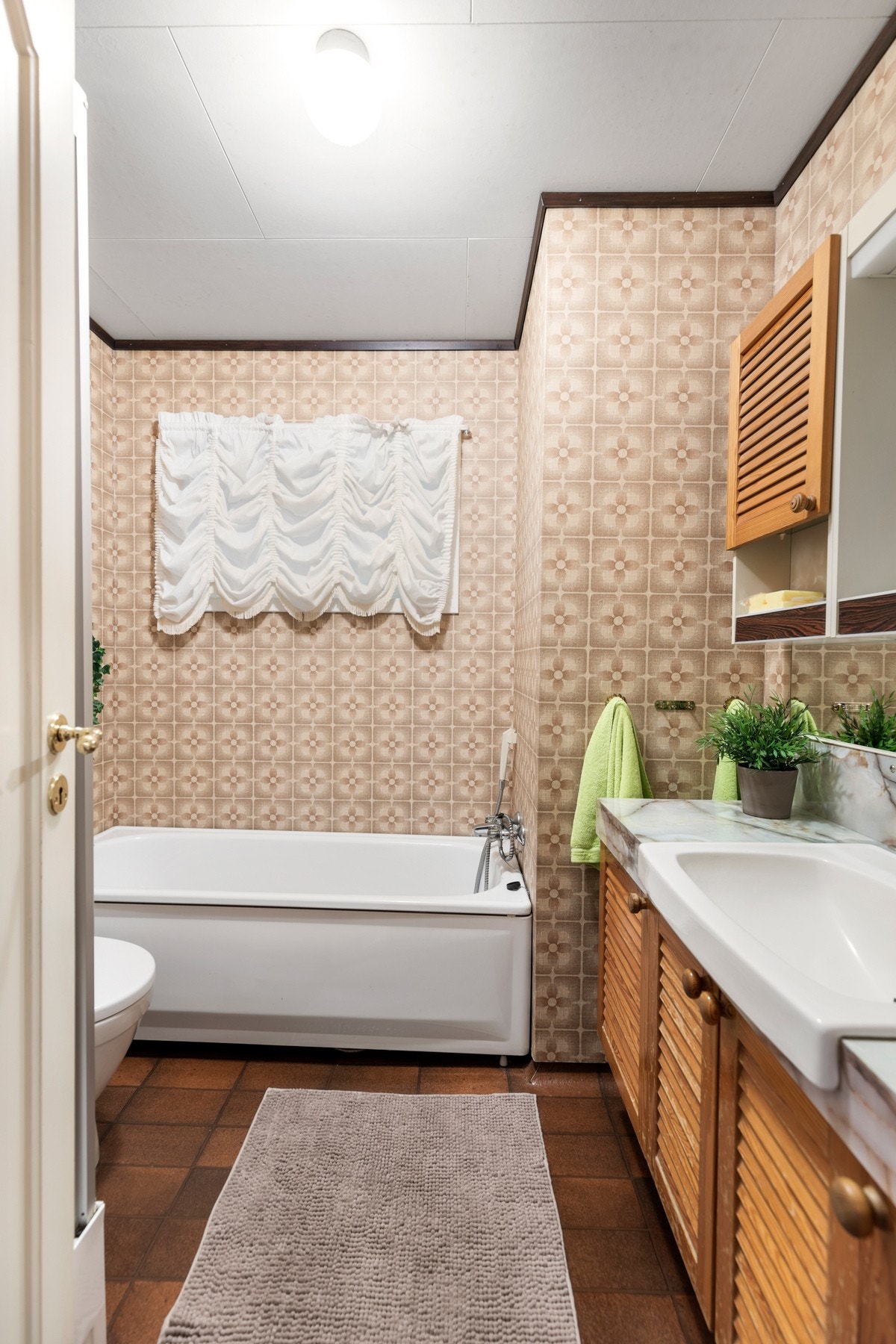 Badet i hovedetasjen er fra byggeår og har flis på gulv og tapet på vegger. Galleribilde