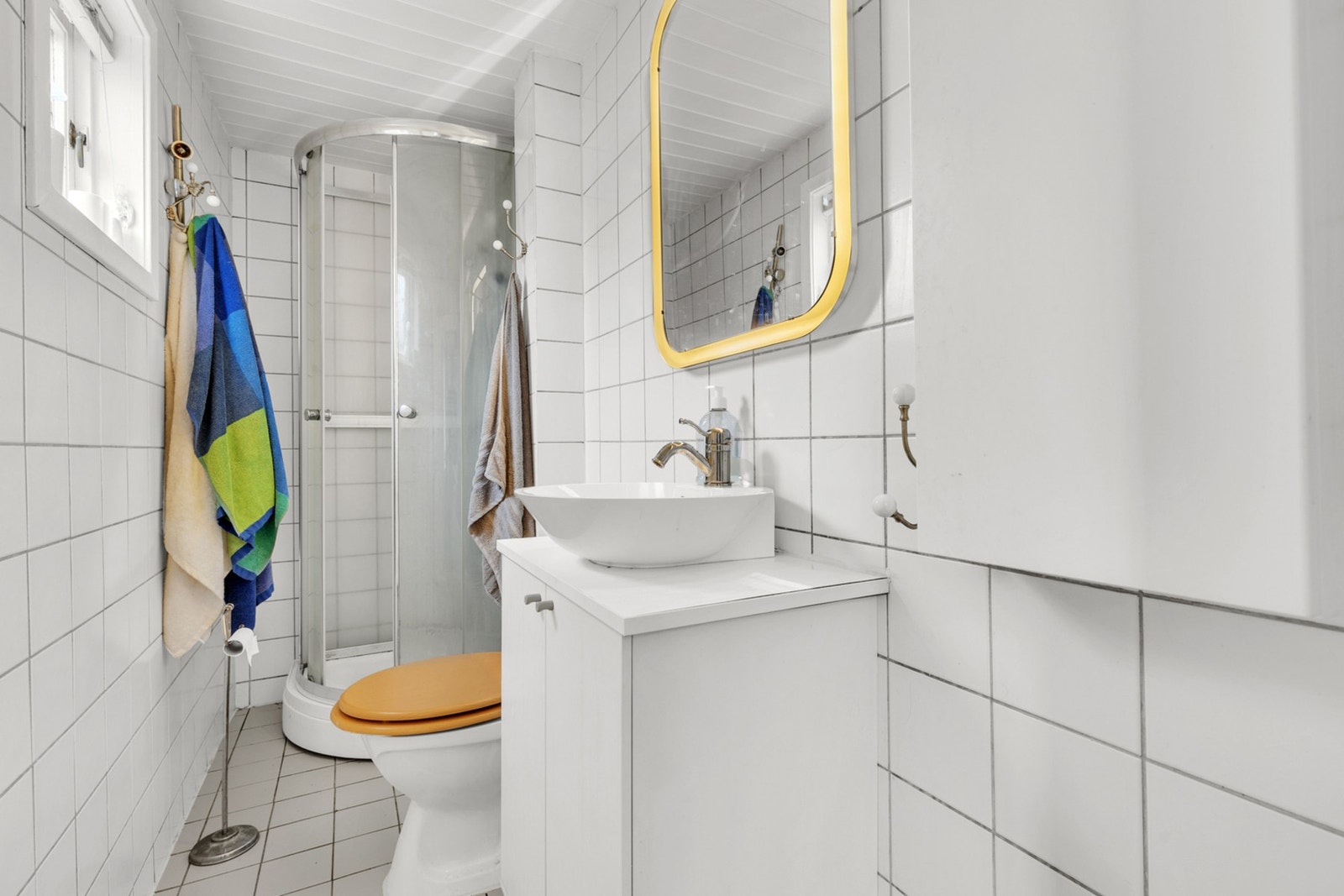 Lyst flislagt bad med bl.a. dusjkabinett og vegghengt innredning med rikelig oppbevaringsplass. Galleribilde