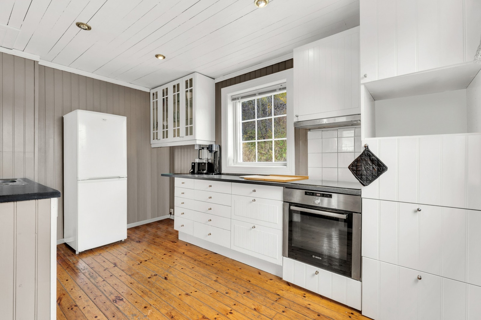 Lyst og pent kjøkken i klassisk stil med mye skap- og benkeplass. Galleribilde