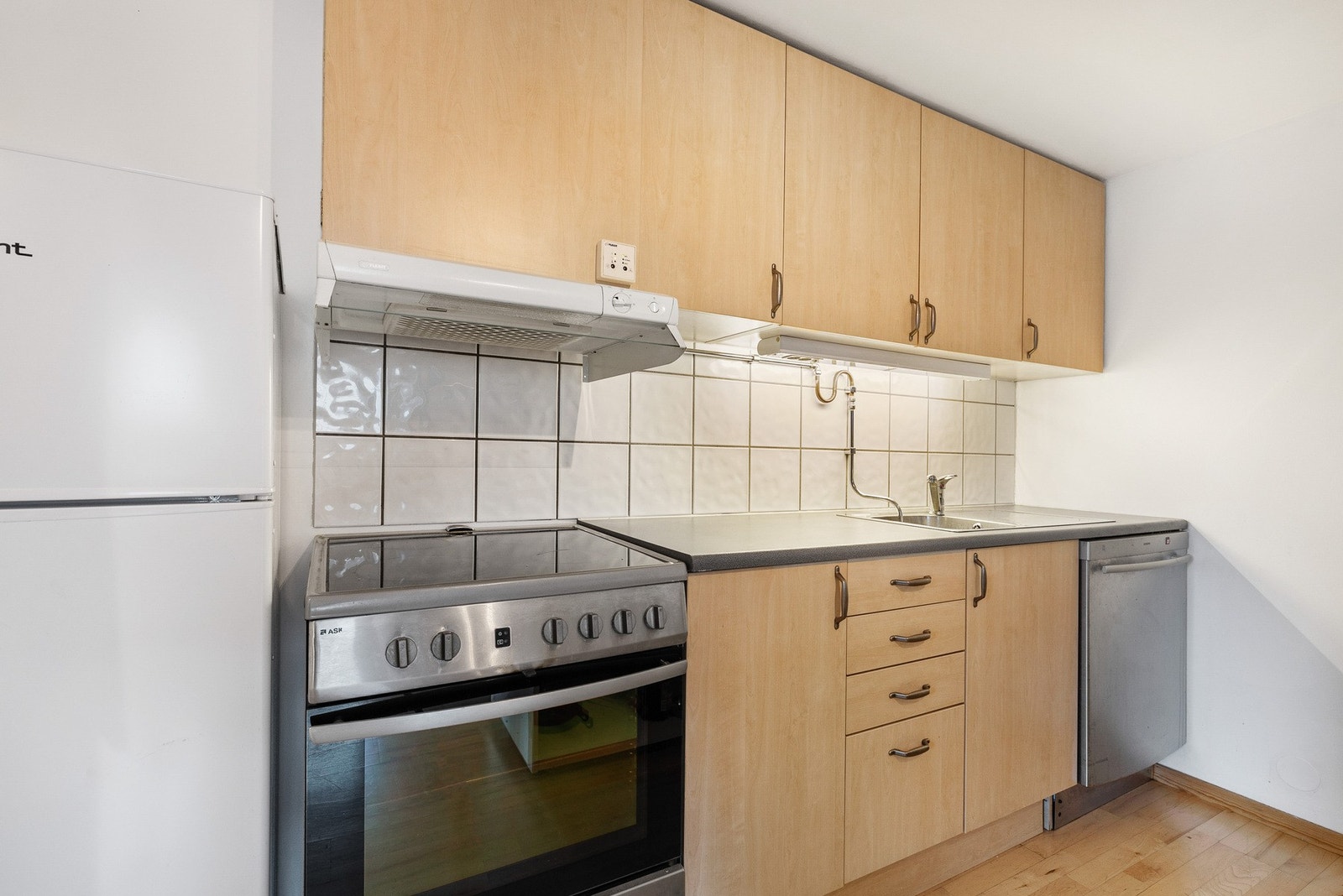 Innredningen har avsatt plass til frittstående hvitevarer og det er montert ventilator tilkoblet avtrekkskanal over platetopp Galleribilde