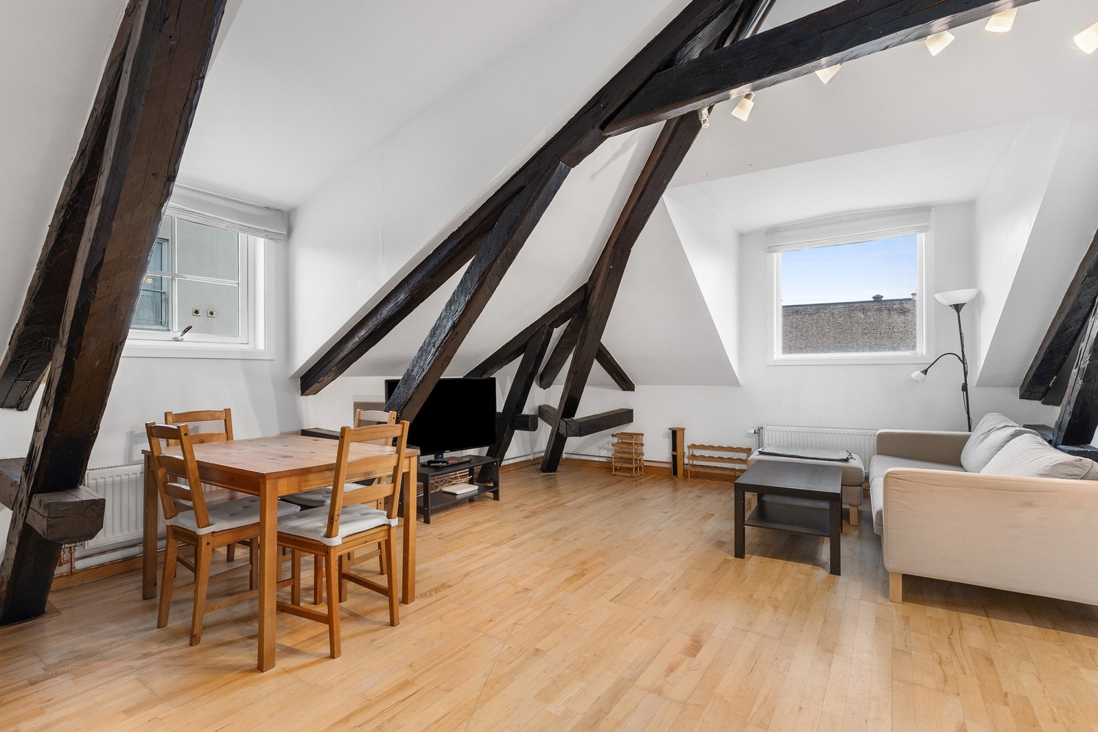 Leiligheten har en lys stue med parkett på gulv og malte, slette overflater på vegger og i himling Galleribilde