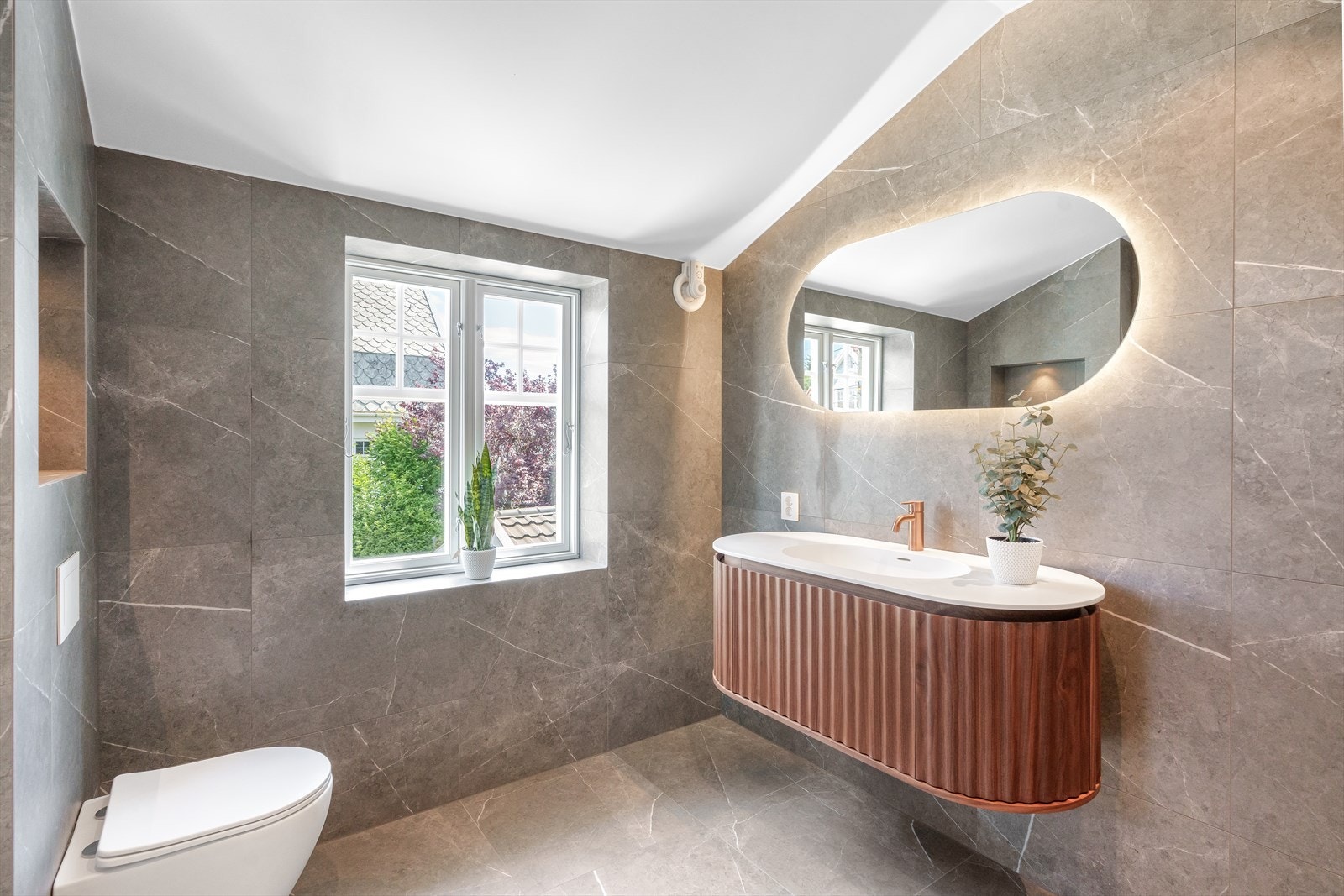 Baderommet har nydelig flislagt gulv og vegger i moderne fargevalg. Lekker baderomsinnredning med god oppbevaring. Flott overspeil med belysning! Dusjnisje og plass til både vaskemaskin og tørketrommel. Vegghengt wc. Galleribilde