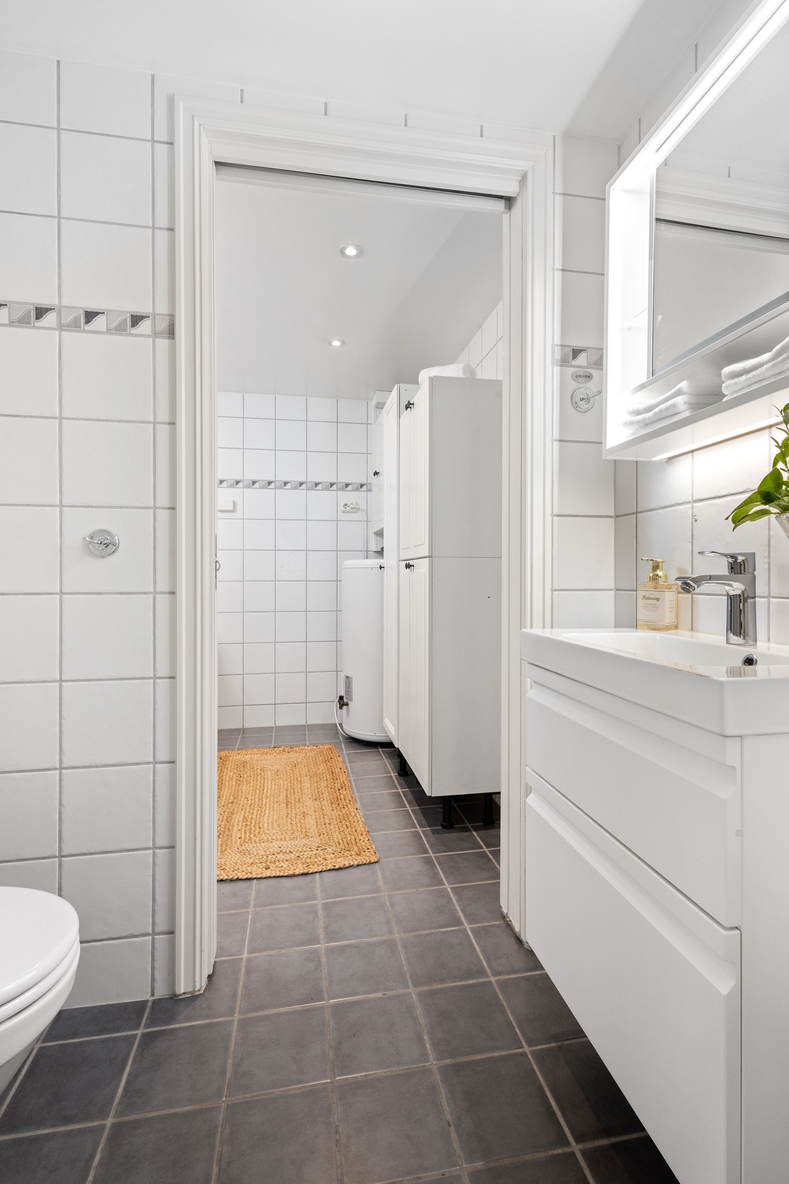 Det andre baderommet er flislagt og innredet med dusjnisje, servant med skuffeseksjon, opplegg for vaskemaskin og skapinnredning. Galleribilde