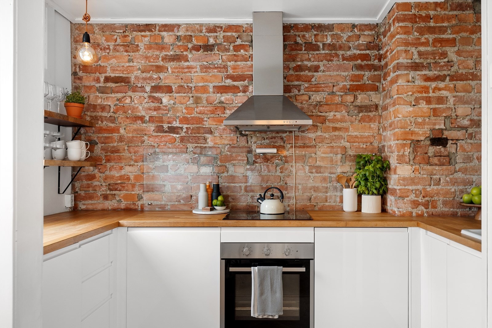 Moderne innredning med glatte, hvite fronter, sprutplate på vegg ved komfyr og heltre benkeplate. Galleribilde