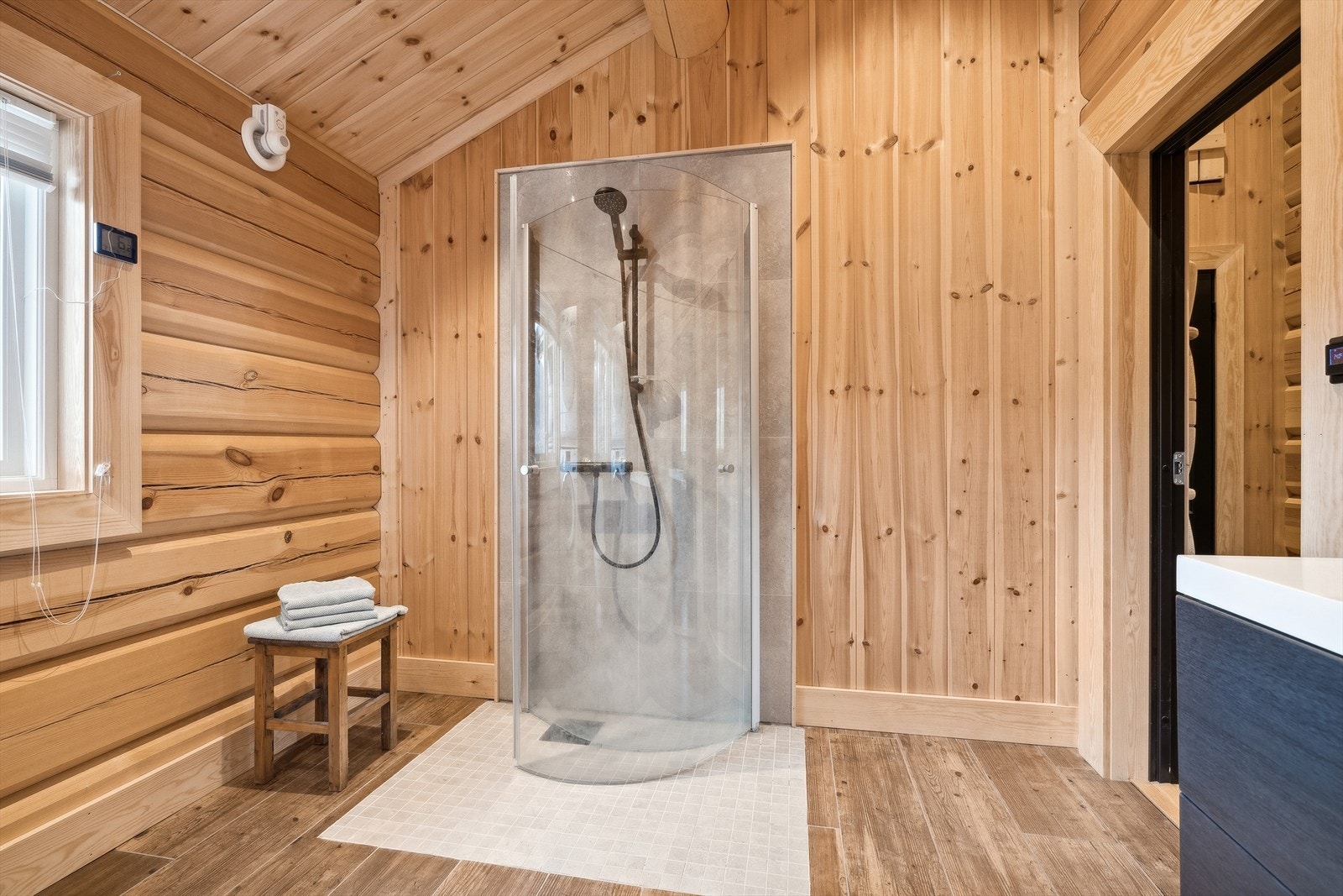 Rommet er utstyrt med dusjarmatur på flisvegg, glassdører ved dusj, avtrekksvifte på yttervegg, gulvmontert toalett, baderomsinnredning med skuffer, heldekkende servant og overskap med speildører. Galleribilde