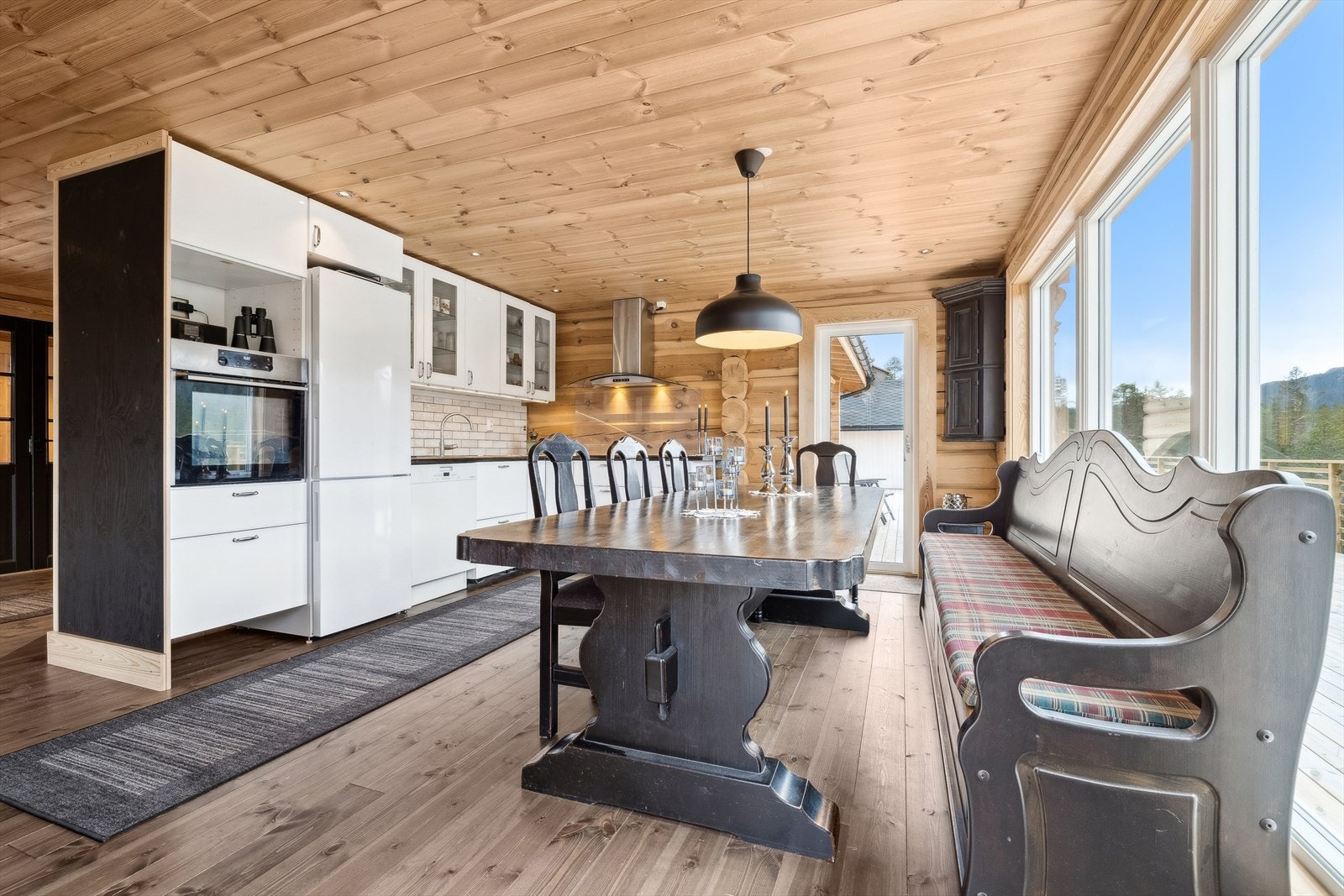 IKEA kjøkkeninnredning fra 2022 i vinkel med hvite fronter, høyglans, glassdører i overskap, overskap på delevegg mot trapp, enkeplate av høyglanspolert stein og nedfelt stålkum. Galleribilde