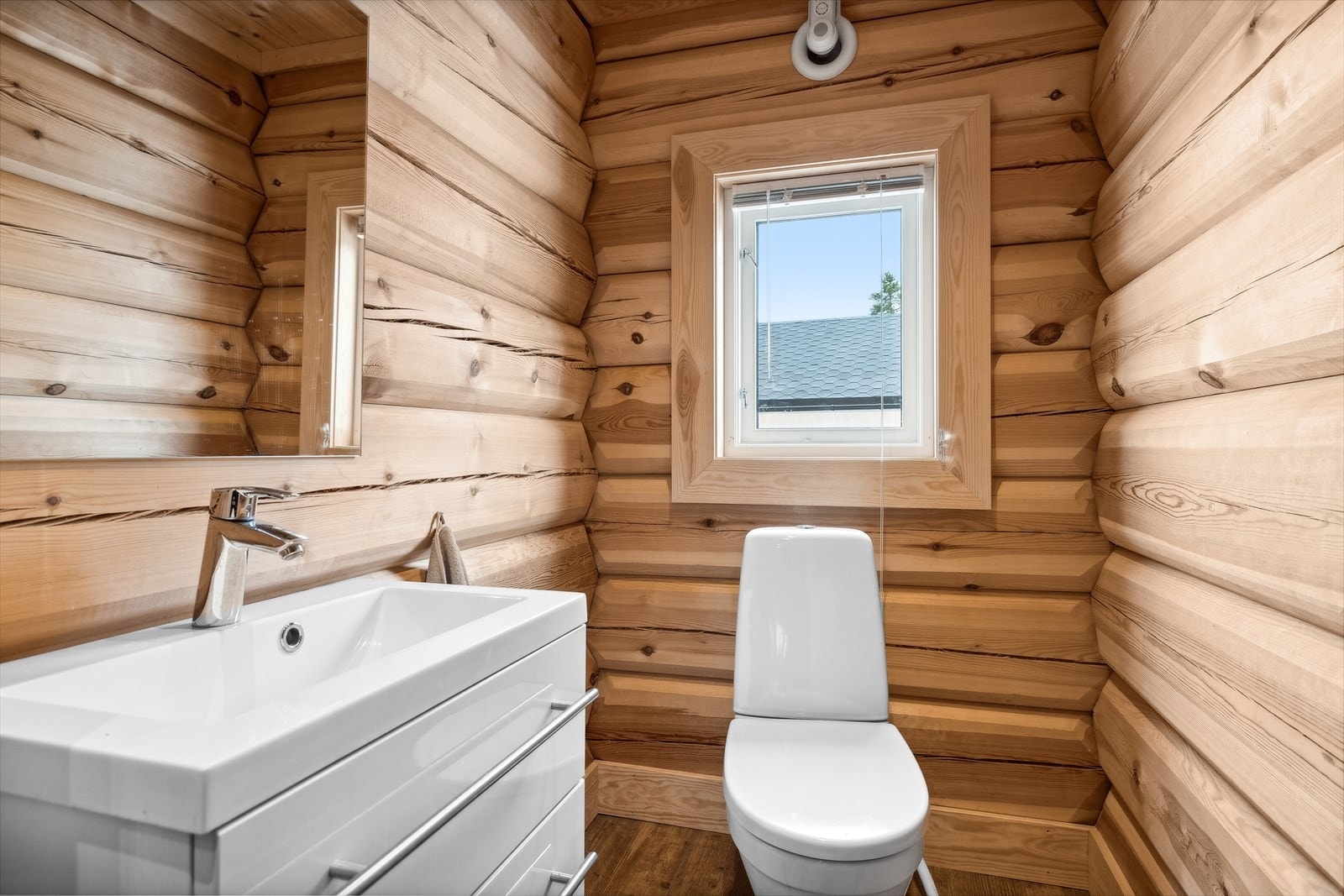 Separat toalettrom med varmekabler i gulv, panel- og tømmervegger, samt panel med LED-spot i himling. Rommet er utstyrt med gulvmontert WC, vask med skuffer i underskap og speil. Det er avtrekksvifte på yttervegg. Galleribilde