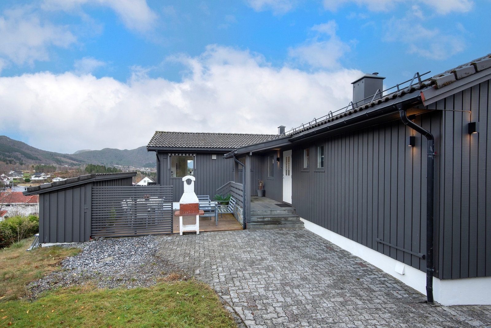 Fasade nordsiden med inngang til boligen og terrasse med utepeis Galleribilde