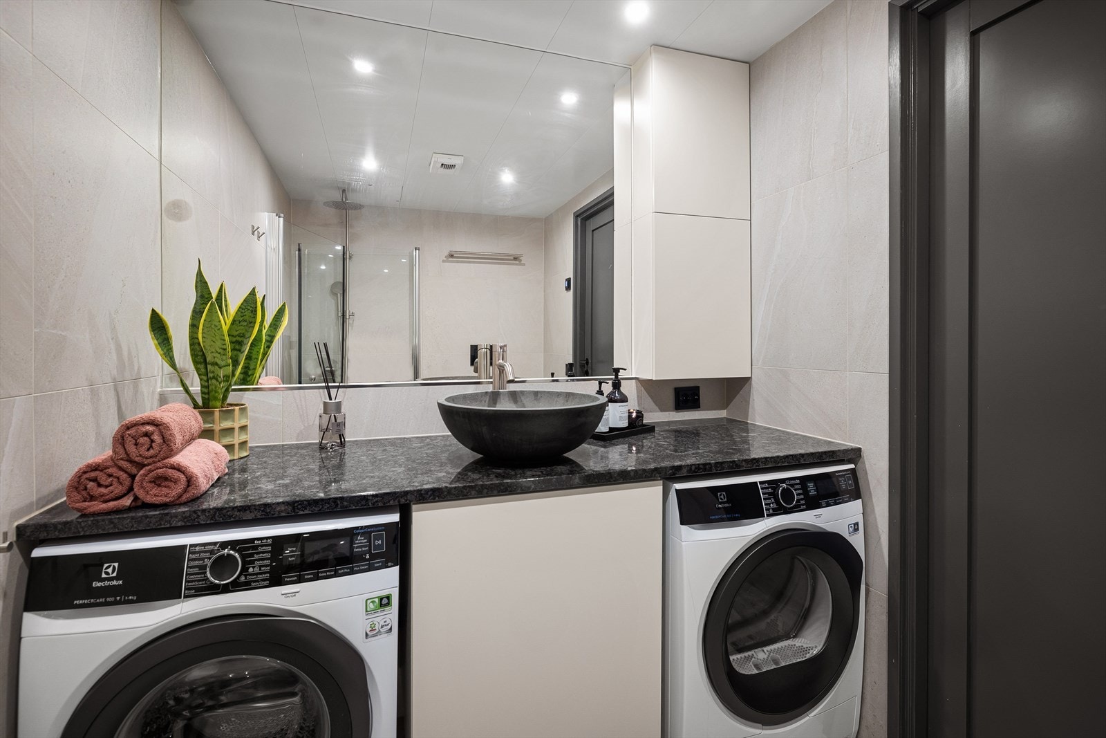 Badet har tidsriktige farge- og materialvalg med fliser, behagelig gulvvarme og downlights i himling. Det er opplegg for vaskemaskin. Galleribilde