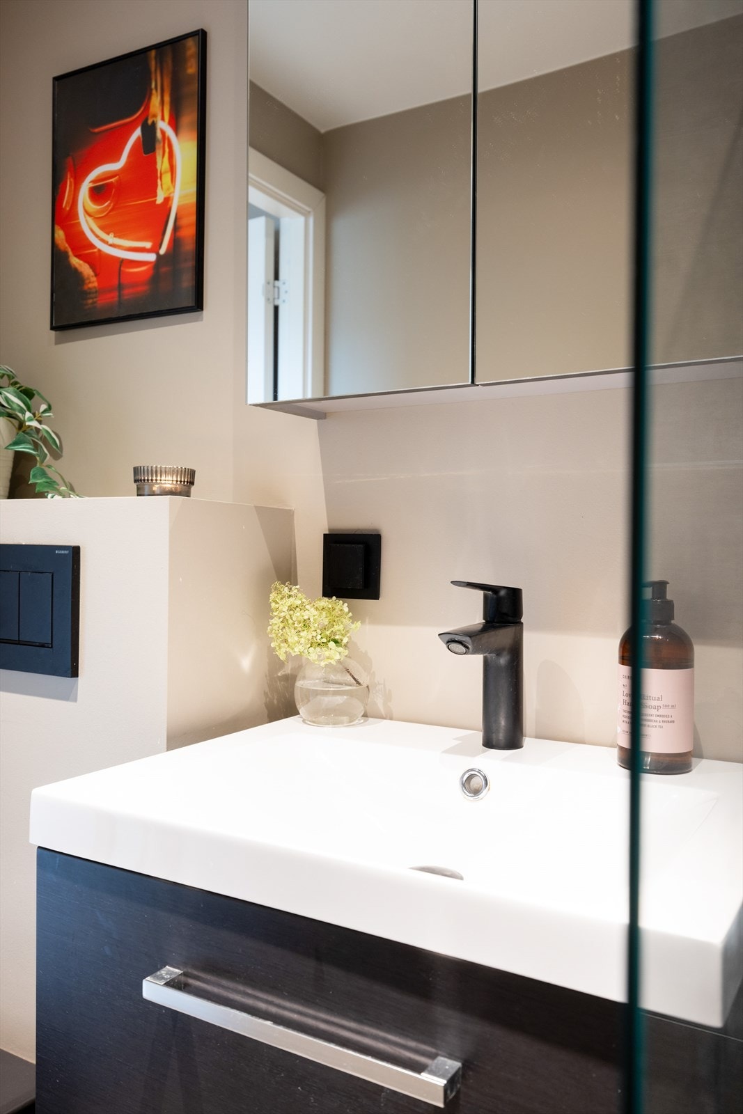 Badet er innredet med vegghengt klosett, servant nedfelt i innredning, speilskap m/lys og dusjhjørne med glassvegg. Galleribilde