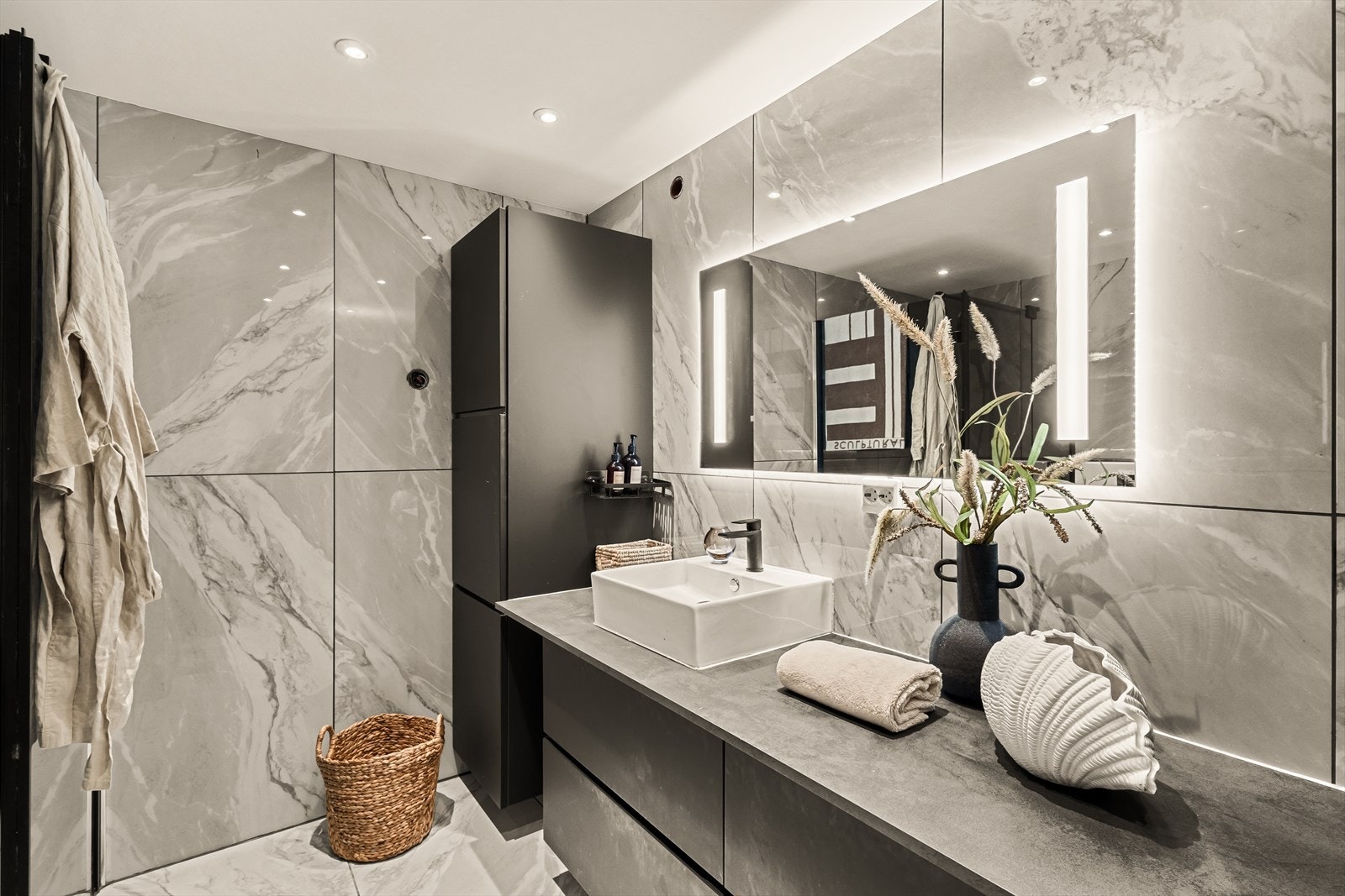 Badet er utstyrt med servant med møblement og speil, belysning, vegghengt toalett og dusjhjørne med dusjgarnityr. Galleribilde