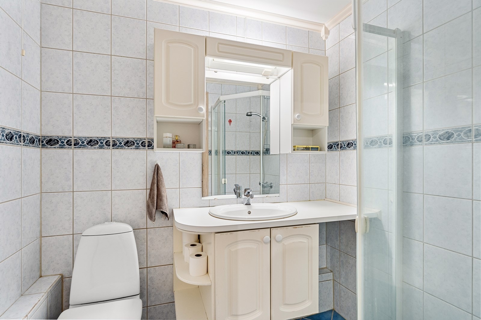 Helfliset bad med toalett, dusjhjørne, servant med møblement, speil og belysning Galleribilde