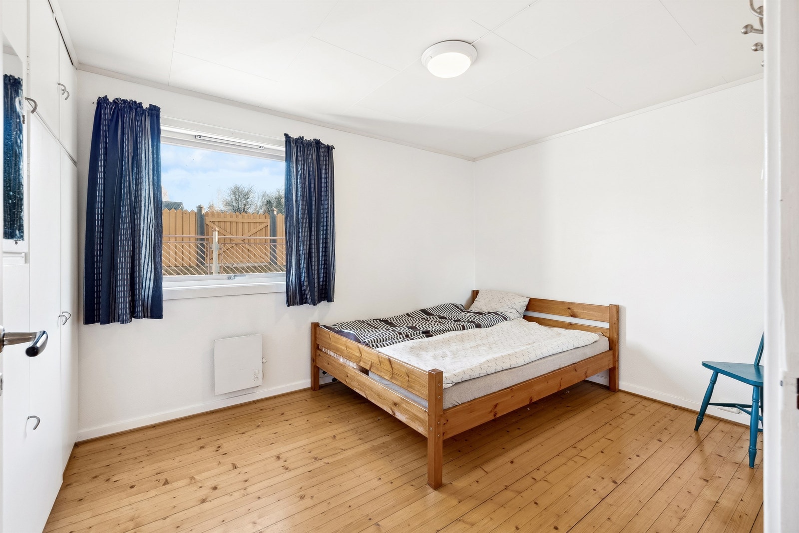 Stort soverom med lysmalte vegger og tregulv. Plassbygde garderobeskap på en hel vegg. Galleribilde