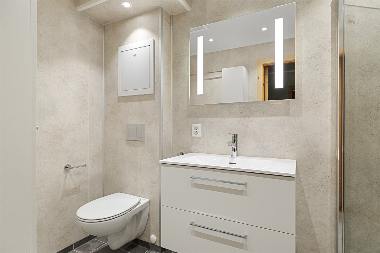 Pent og moderne bad fra 2022 med flislagt gulv med elektriske varmekabler og opplegg til vaskemaskin. Galleribilde