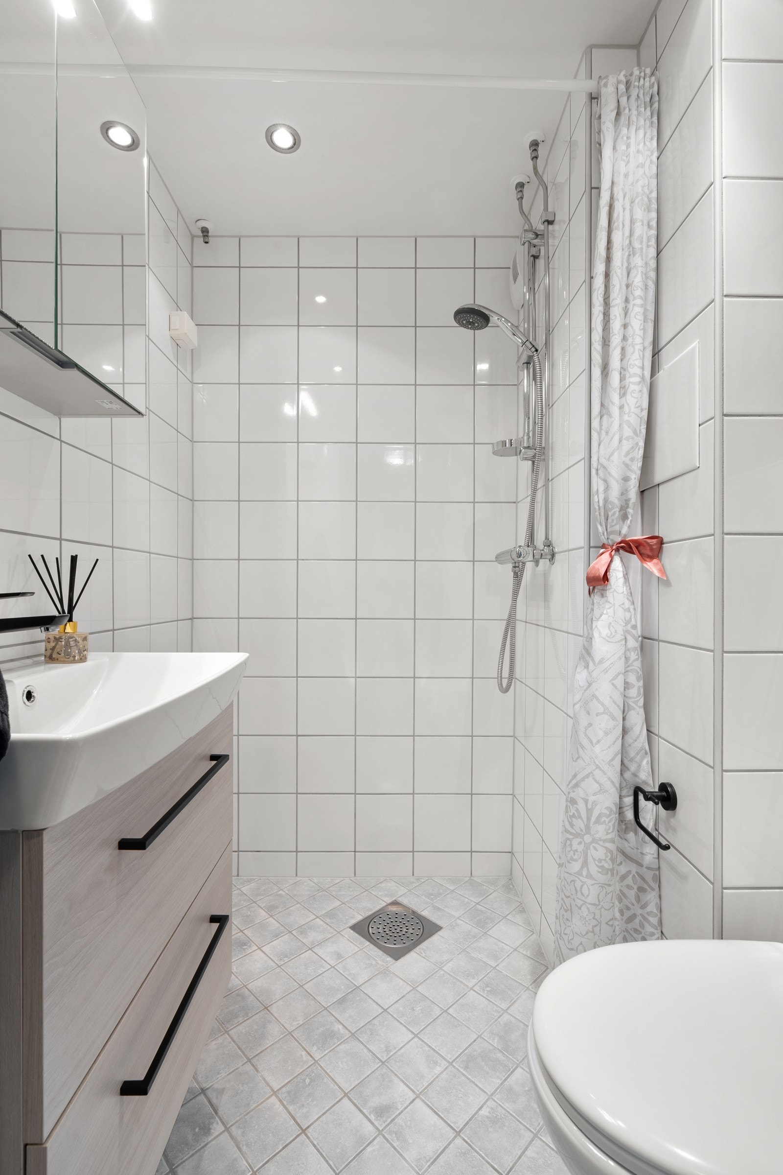 Videre har badet veggmontert klosett og dusjesone Galleribilde