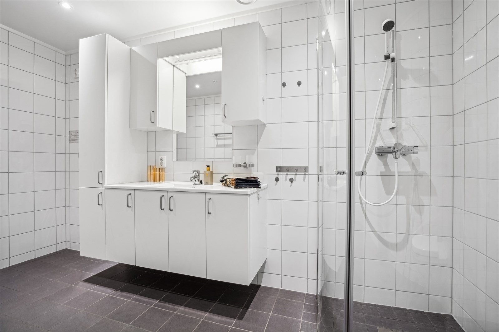 Badet er utstyrt med en stor servantinnredning, dusjhjørne, toalett og opplegg for vaskemaskin. Galleribilde