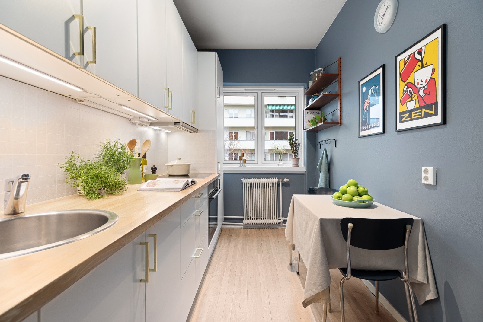 Stilrent kjøkken innredet med slette fronter, overskap med benkebelysning og veggplater Galleribilde