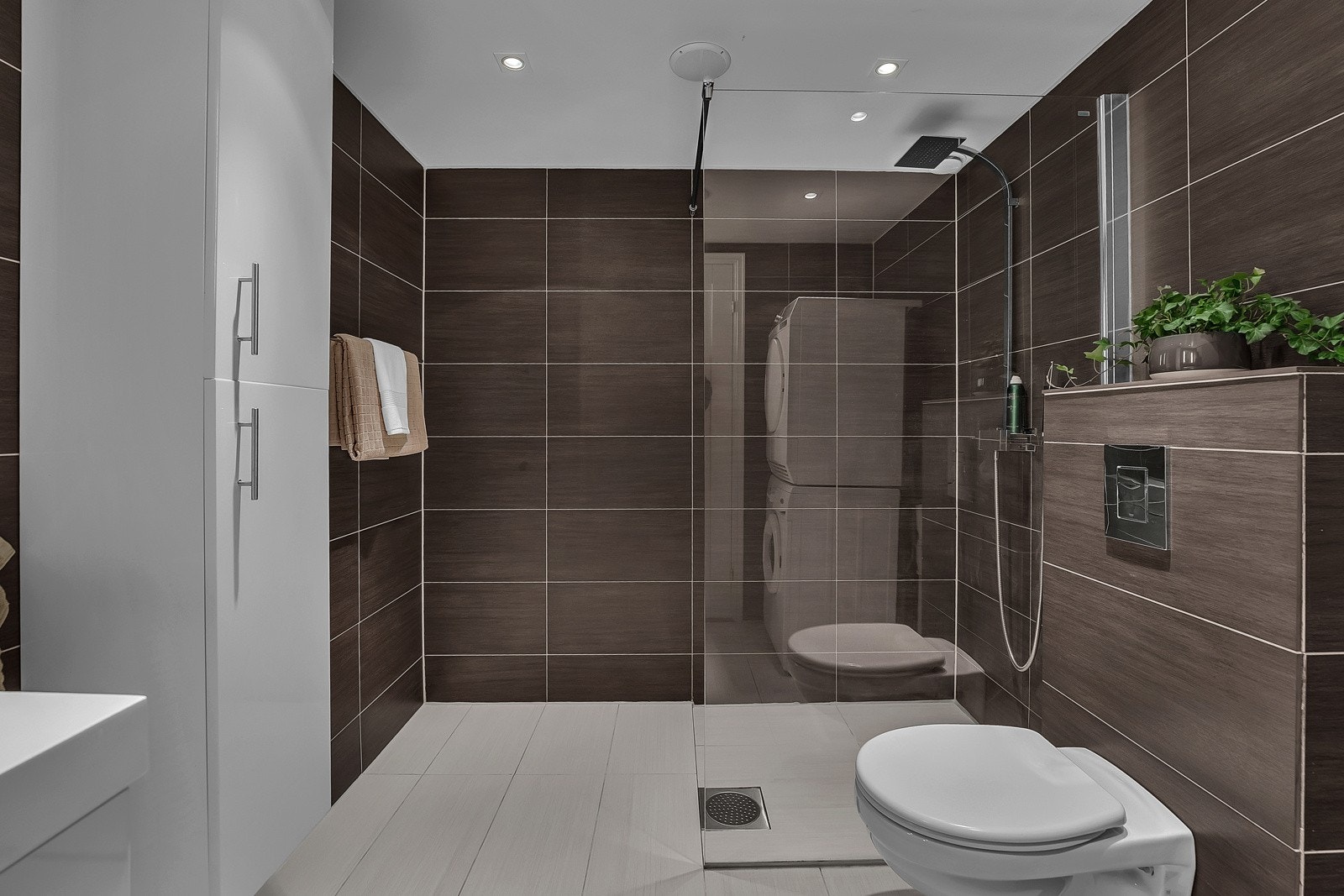 Badet er utstyrt med veggfestet toalett, dusjhjørne med skillevegg i glass og opplegg for vaskemaskin. Galleribilde