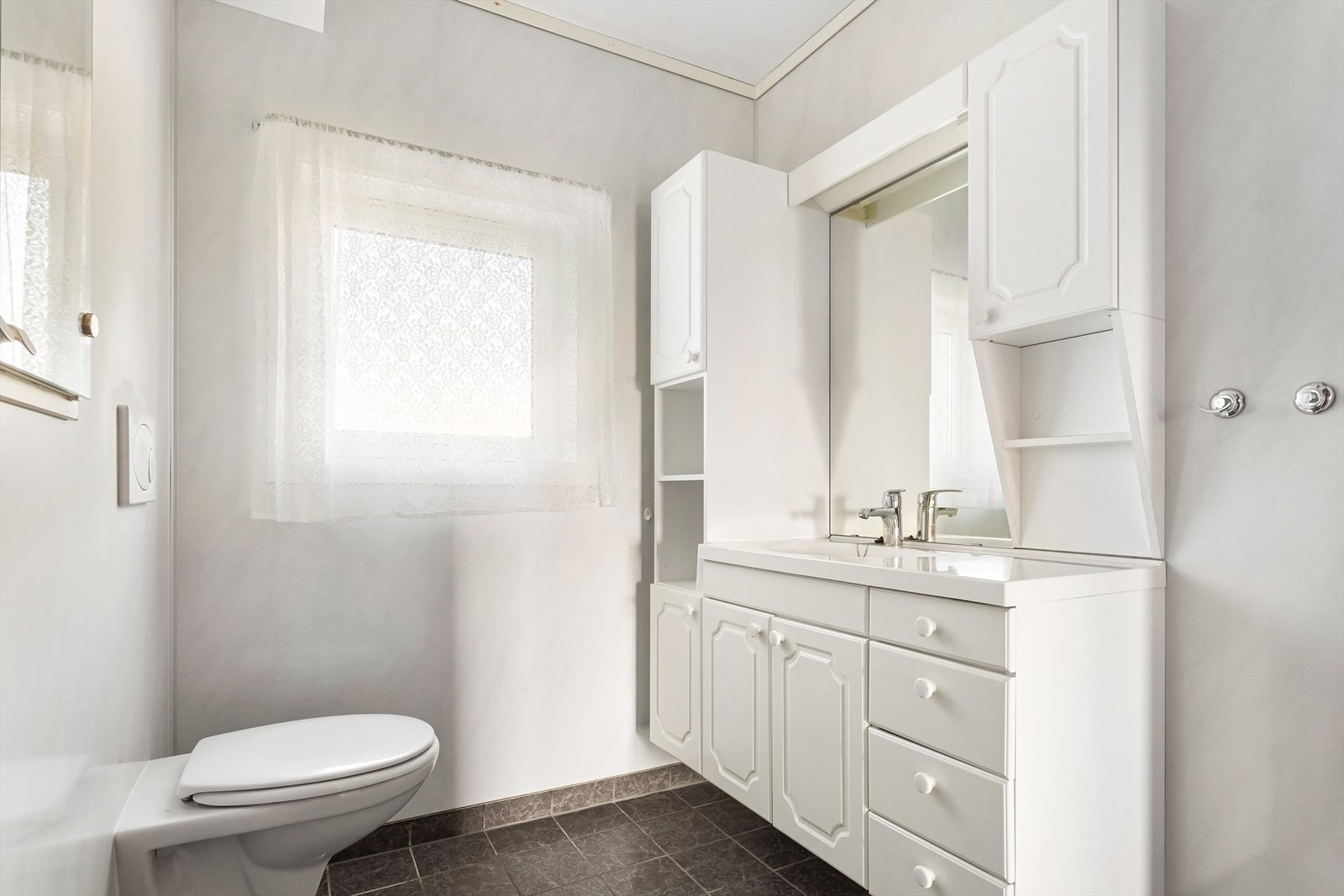 Badet er utstyrt med servant, toalett og dusjhjørne med foldedører i glass Galleribilde