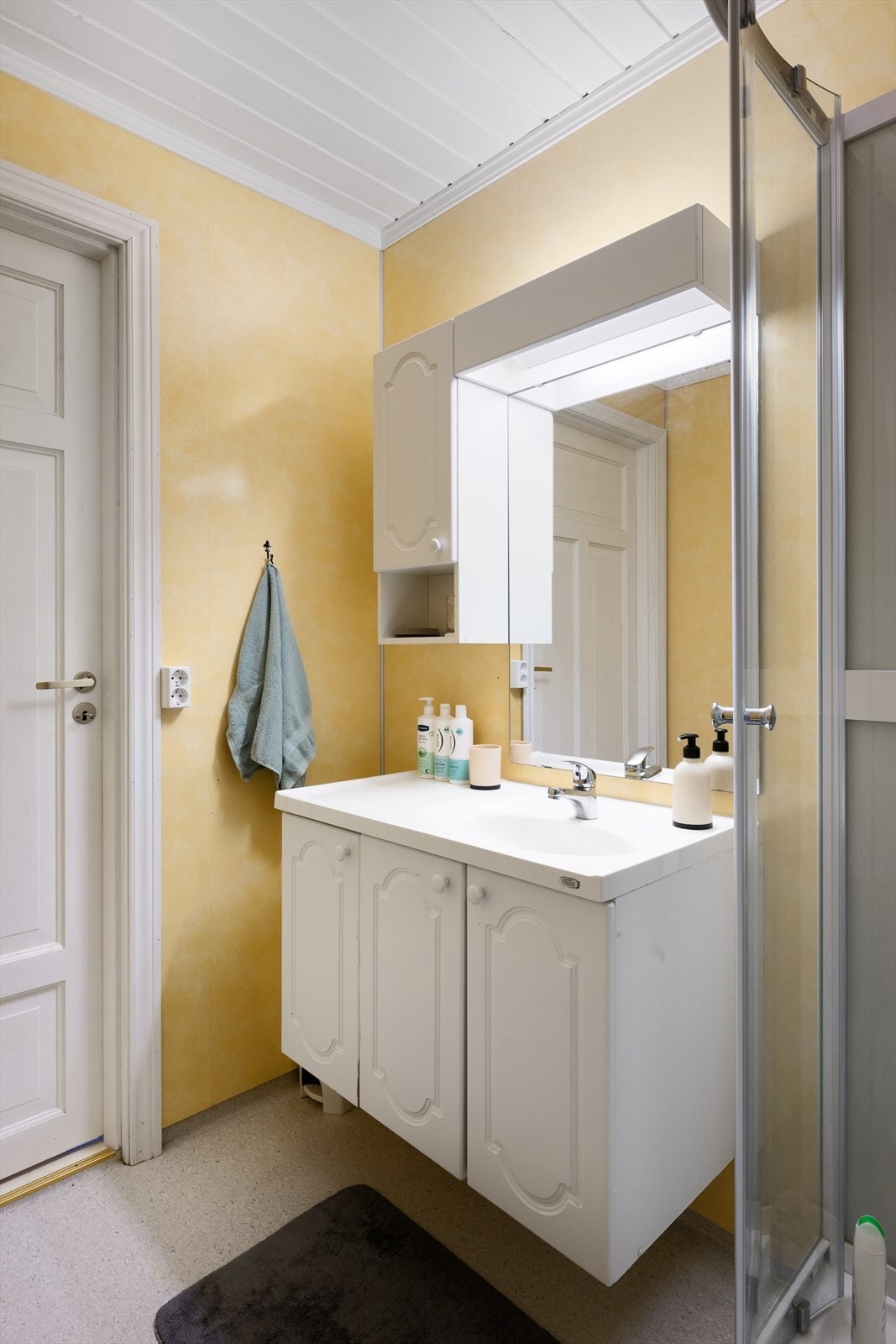 Det er vinylbelegg på gulv, baderomsplater på vegger og trepanel i himling. Galleribilde