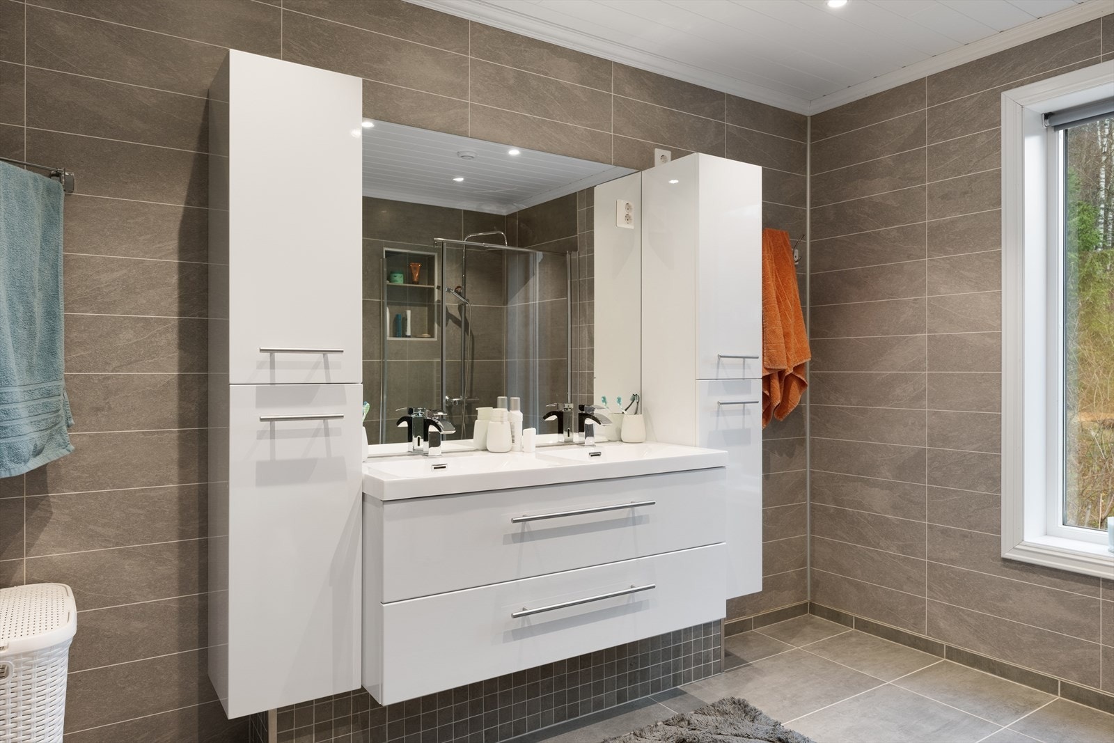 Rommet er innredet med 2 nedfelte servanter, veggmontert toalett og dusjnisje med glassdør. Galleribilde