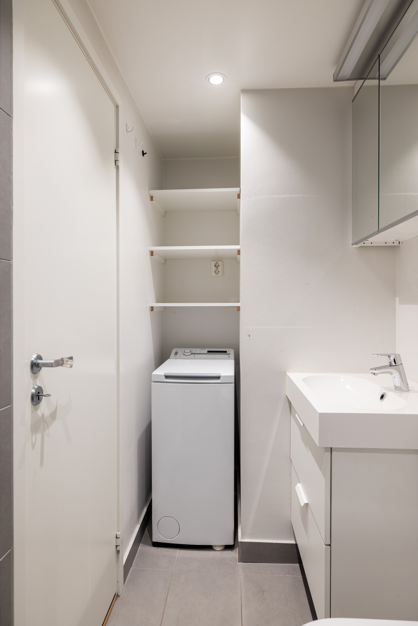 Badet er utstyrt med en dusjnisje med innfellbar dusjvegg, veggmontert servantskap med heldekkende vask, gulvvarme og opplegg for vaskemaskin Galleribilde