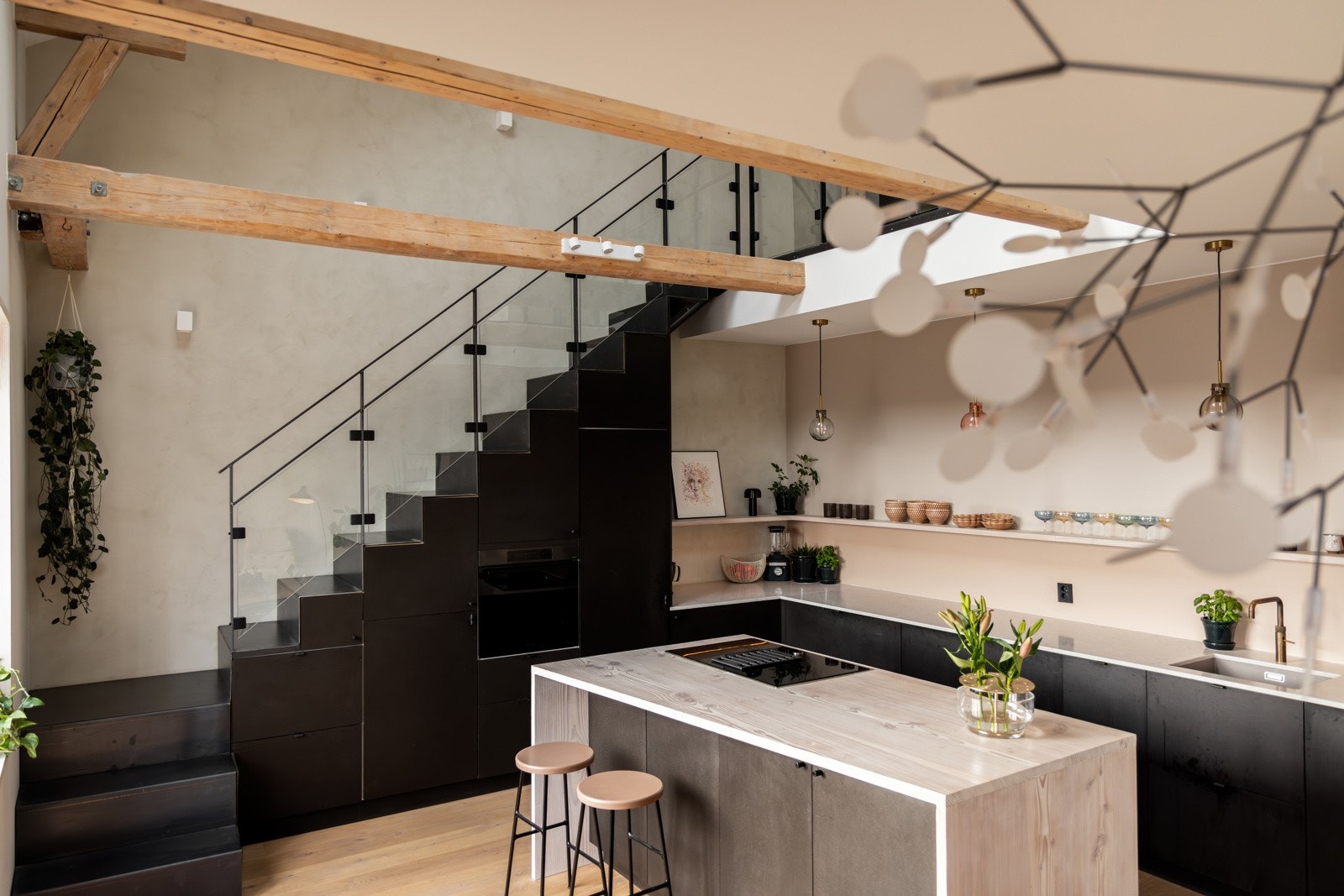 Leiligheten byr på et stilrent kjøkken. Innredningen er fra Kvik med sorte fronter i Valcromat, kombinert med tilpassede skap i finér under trappen som gir en sømløs overgang og praktisk oppbevaring Galleribilde