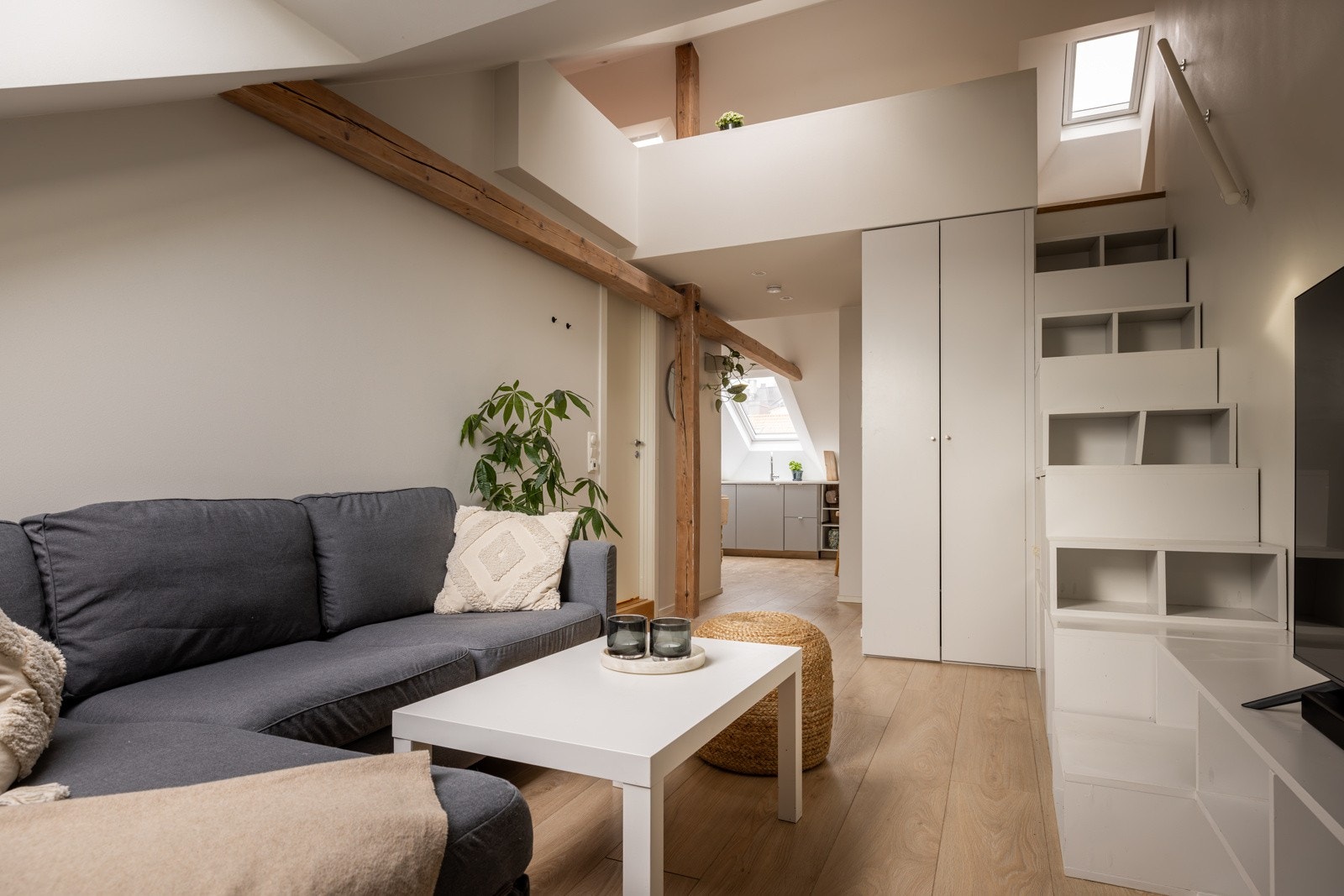 Hybelen har en praktisk hems som nås via en trapp fra stuen. Trappen til hemsen er utformet med smarte, tilpassede rom for oppbevaring, noe som gir en effektiv utnyttelse av plassen i hybelen Galleribilde
