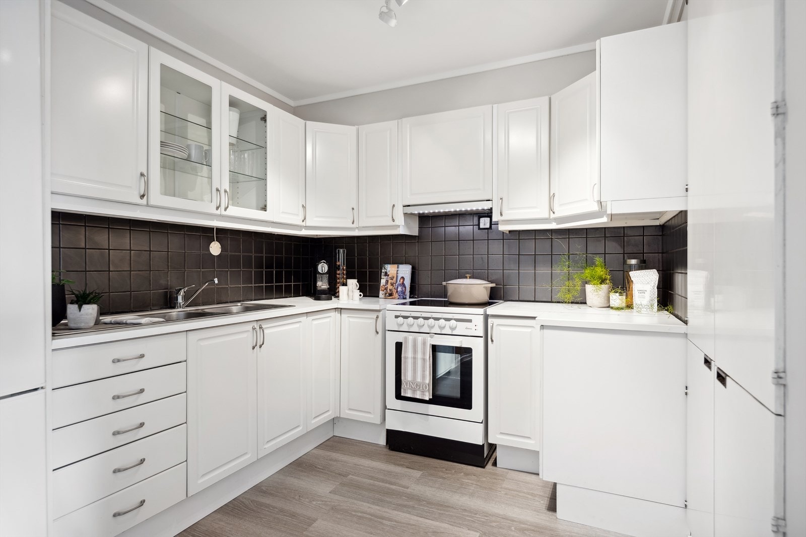 Pent kjøkken fra Ikea med profilerte fronter, laminat benkeplate og fliser over kjøkkenbenken. Meget god skapplass! Høyskap til høyre for langkost og støvsuger lagring. Galleribilde