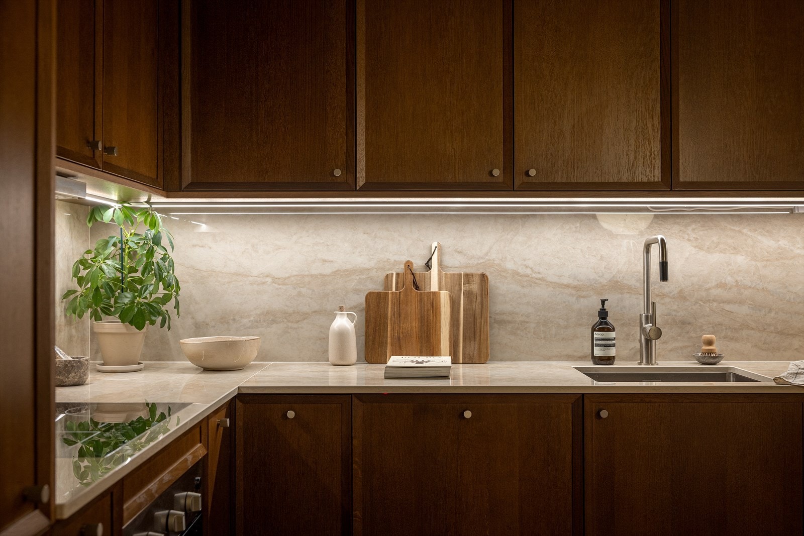 Boligen har et lekkert kjøkken med benkeplate og backsplash i samme design, som skaper en sømløs finish. Det er lagt lysskinner under overskapene som gir kjøkkenområdet en hyggelig belysning. Galleribilde