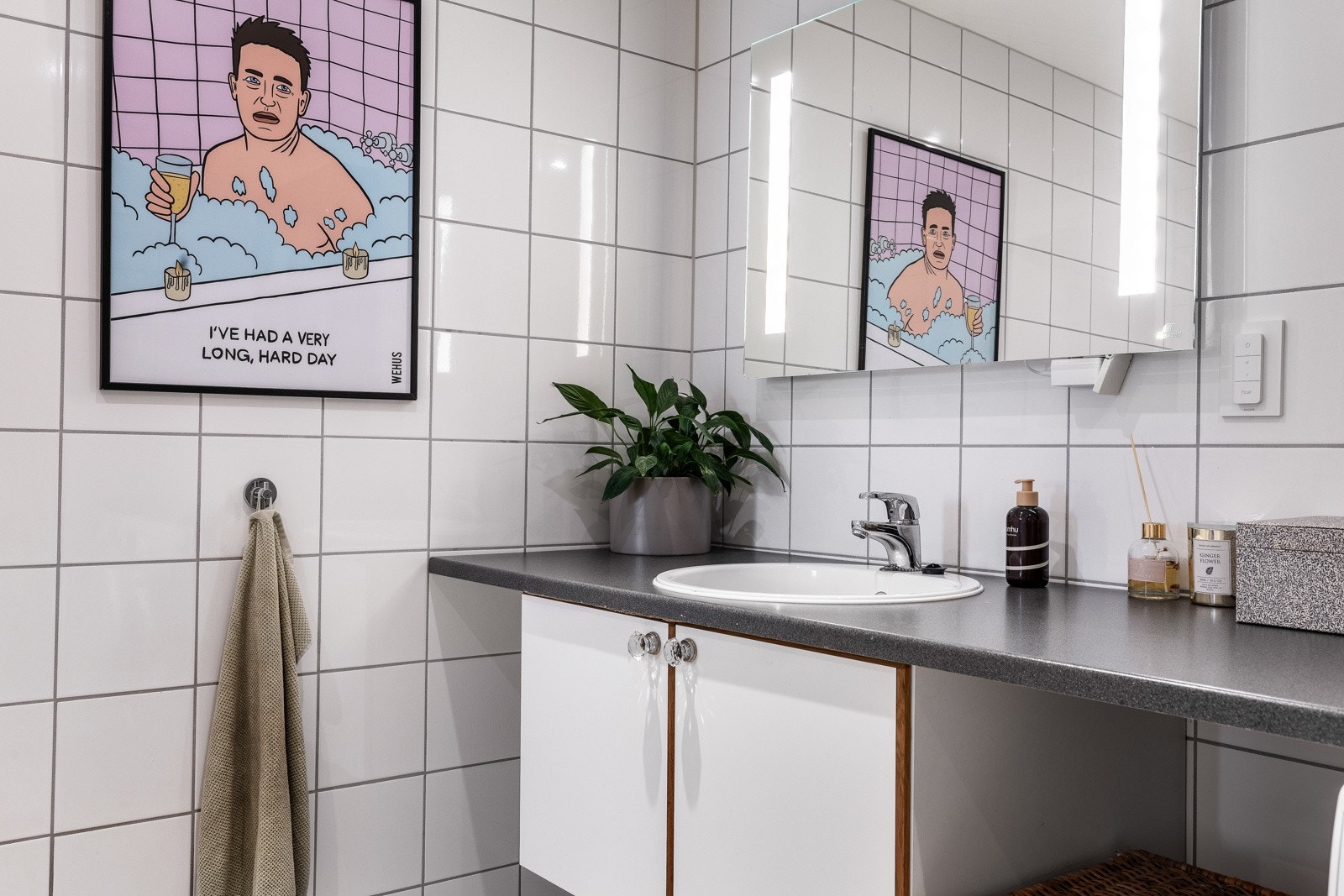 Baderomsinnredningen består av en nedfelt servant i en koksgrå benkeplate, et hvitt, dobbelt underskap og et stort speil med integrert belysning. Galleribilde