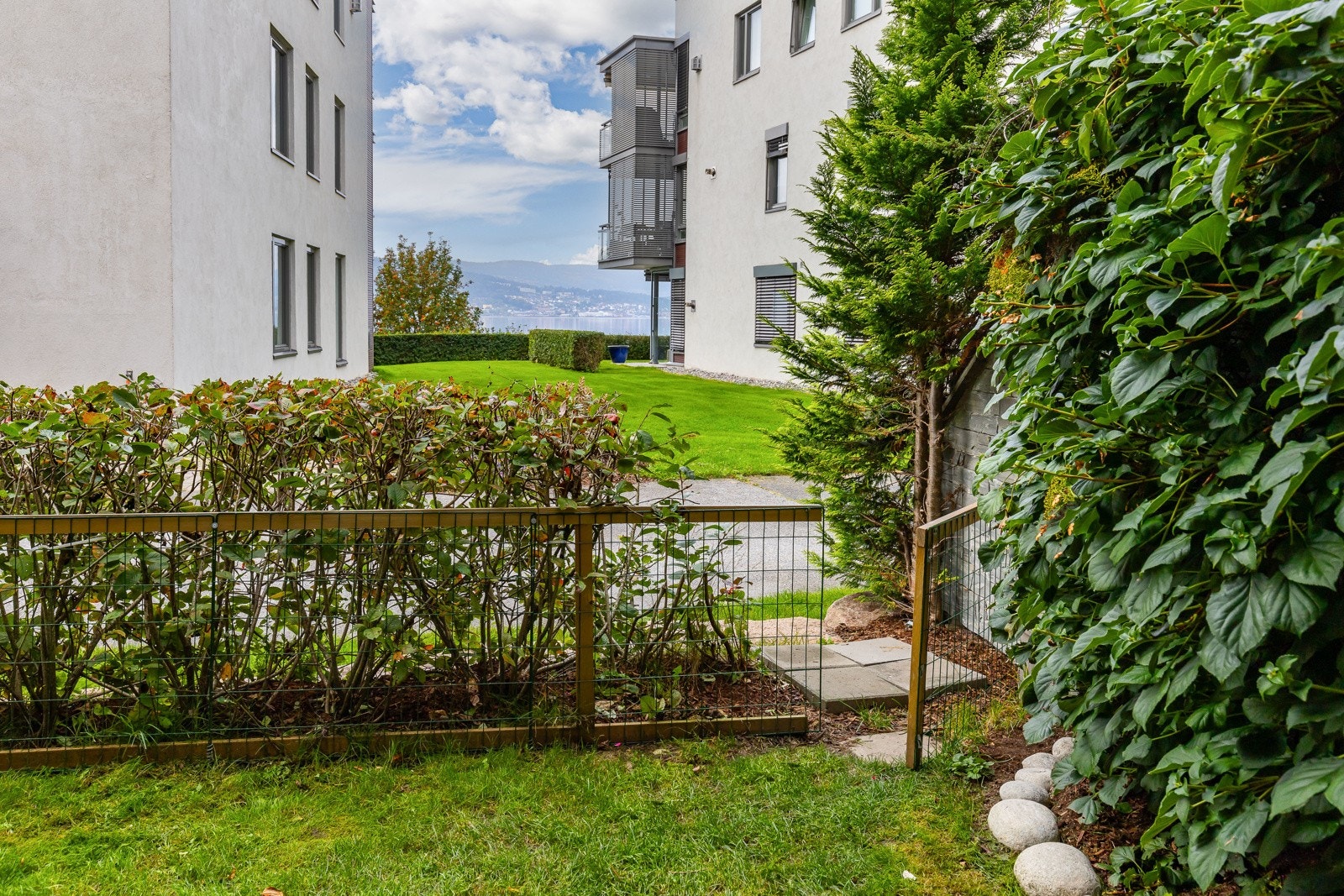Markterrassen har hellelagt dekke, og ligger i flukt med en egen hage med gressplen og omkransende hekk. Galleribilde