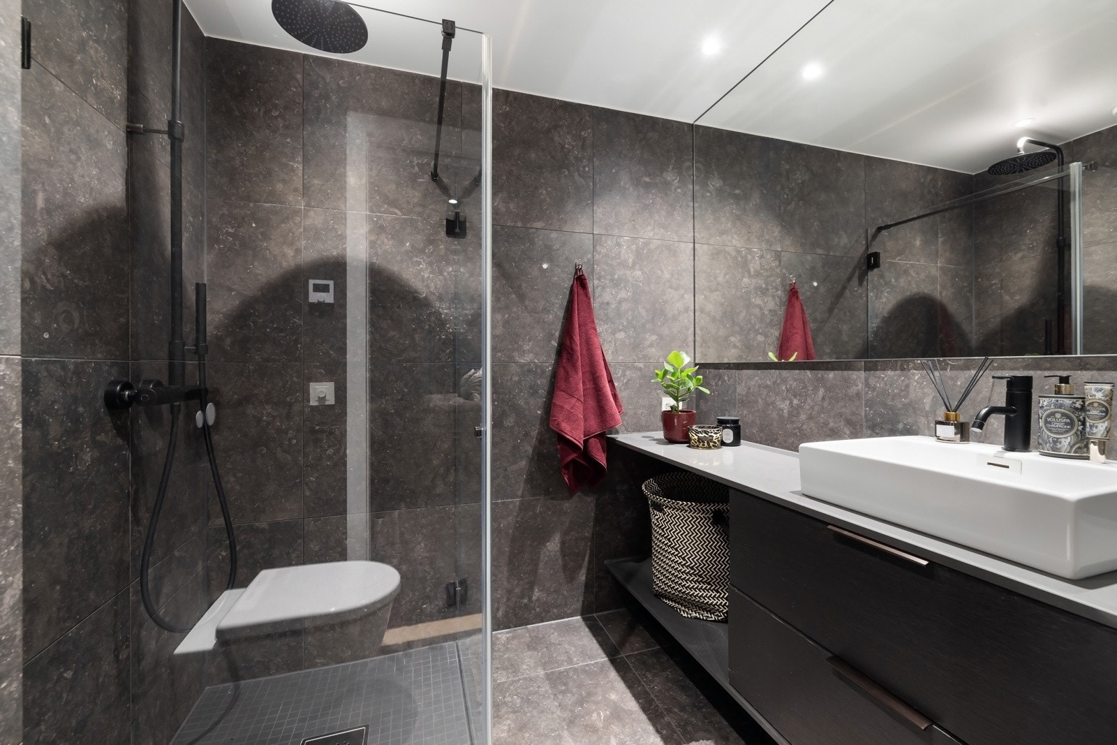 Bad 1 (2 etasje) - Flislagt bad/wc med vannbåren varme, avtrekk, speil, downlights, stein/kompositt benkeplate med servant og innredning, dusj hjørne med innfelbar glassdør og vegghengt toalett. Galleribilde
