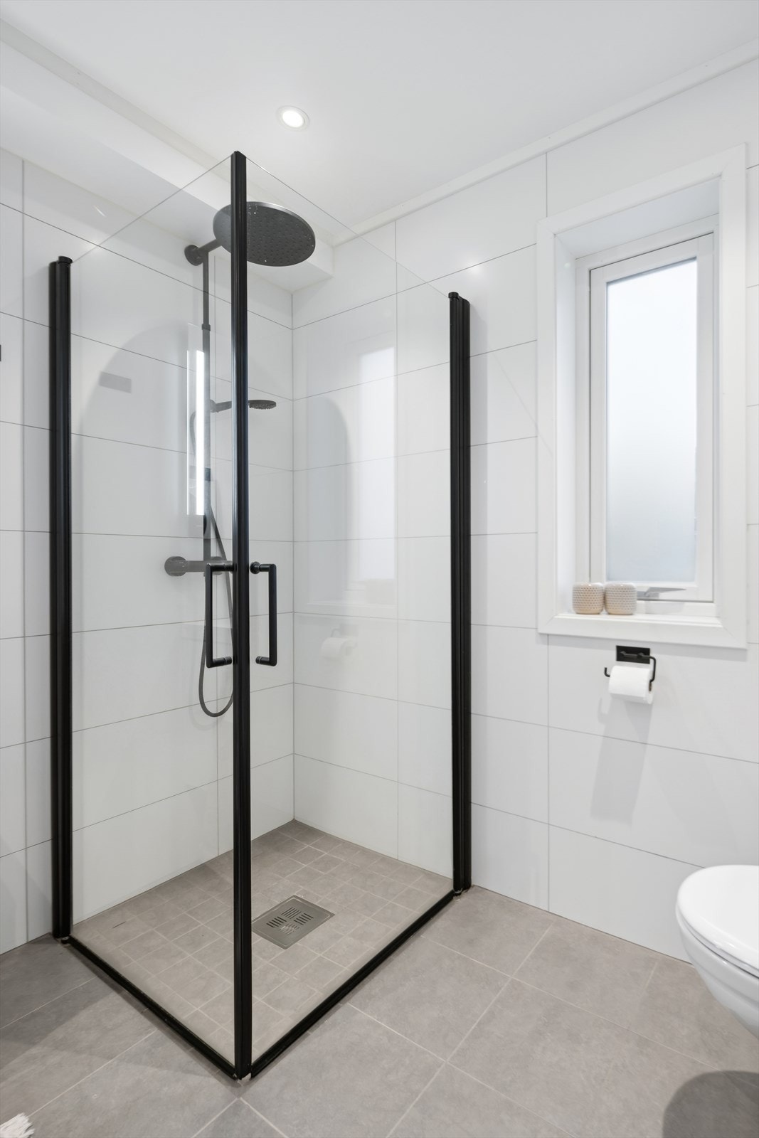 Badet er utstyrt med vegghengt toalett, dusjhjørne med glassvegg, samt baderomsinnredning med nedfelt servant. Galleribilde