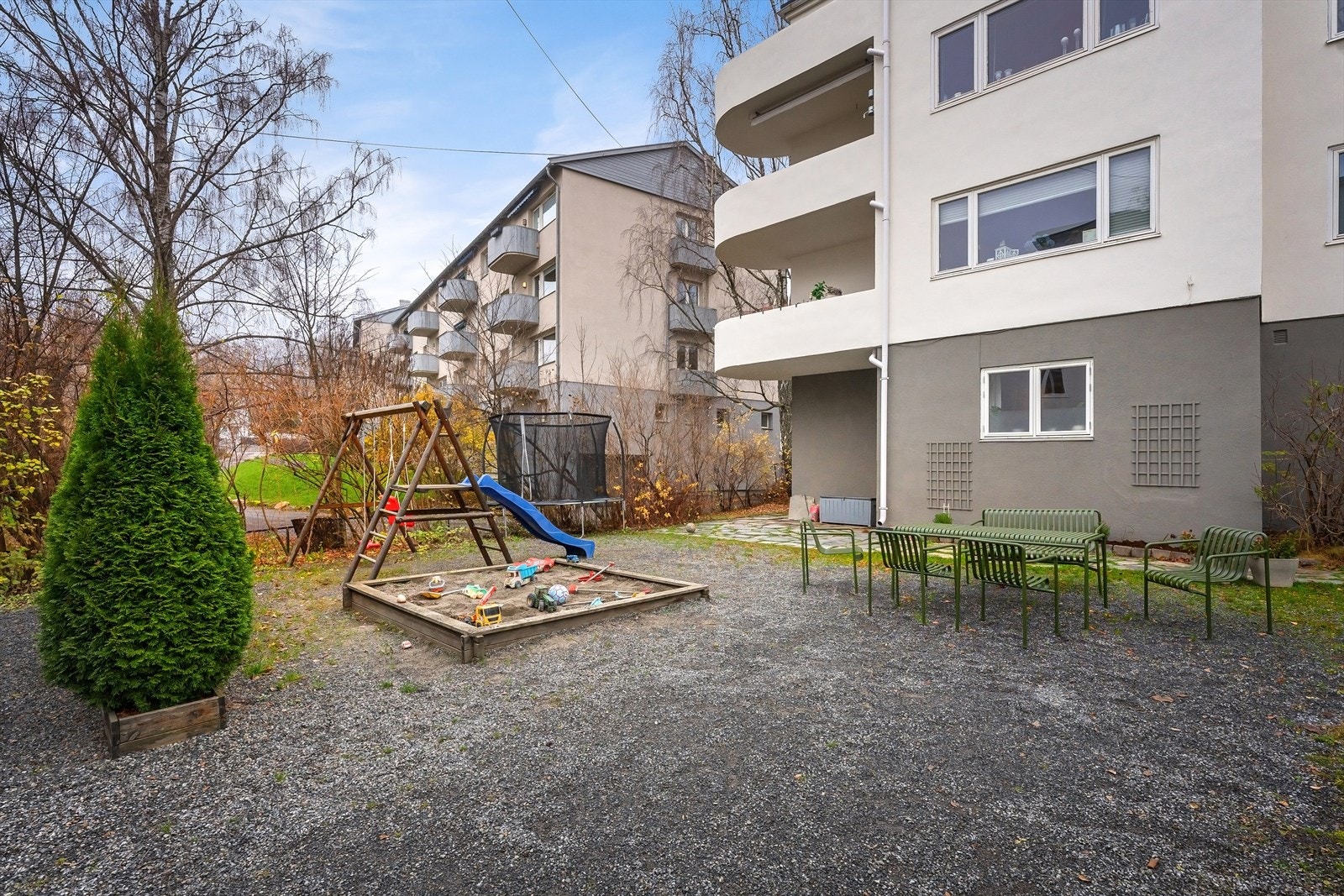 Hyggelig fellesområder med gruset plass, plenarealer, sittegruppe og lekeområde Galleribilde