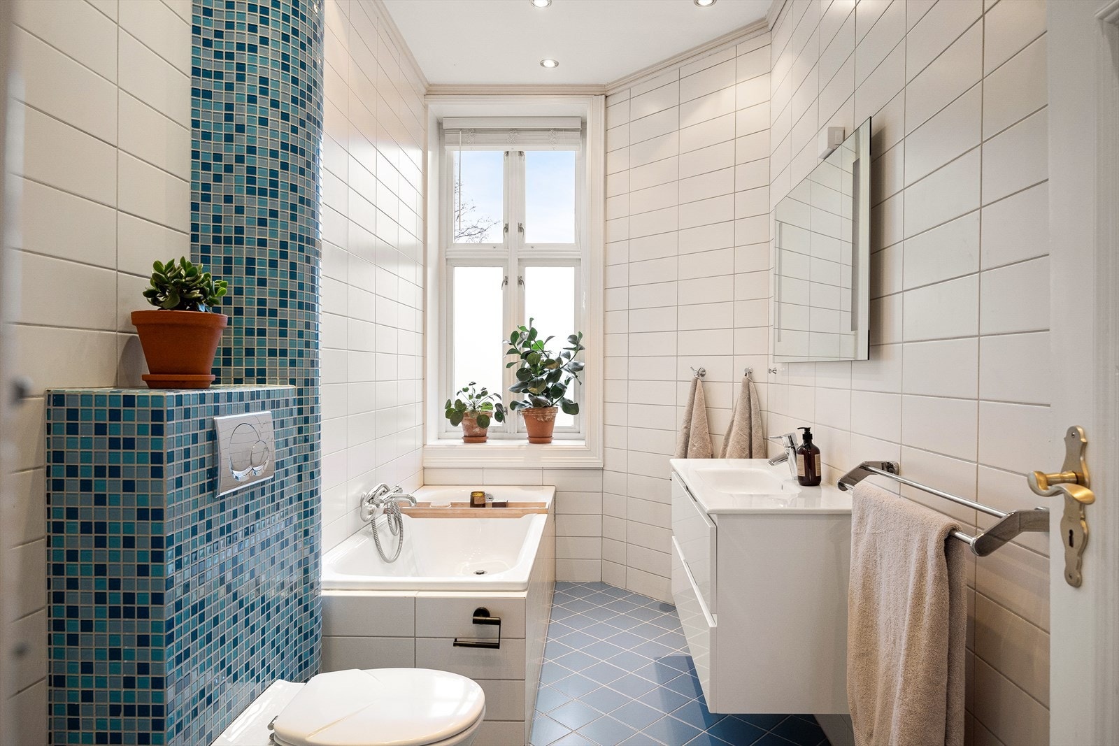 Boligen har et flislagt bad med downlights, badekar og dusjhjørne med glassdører. Galleribilde