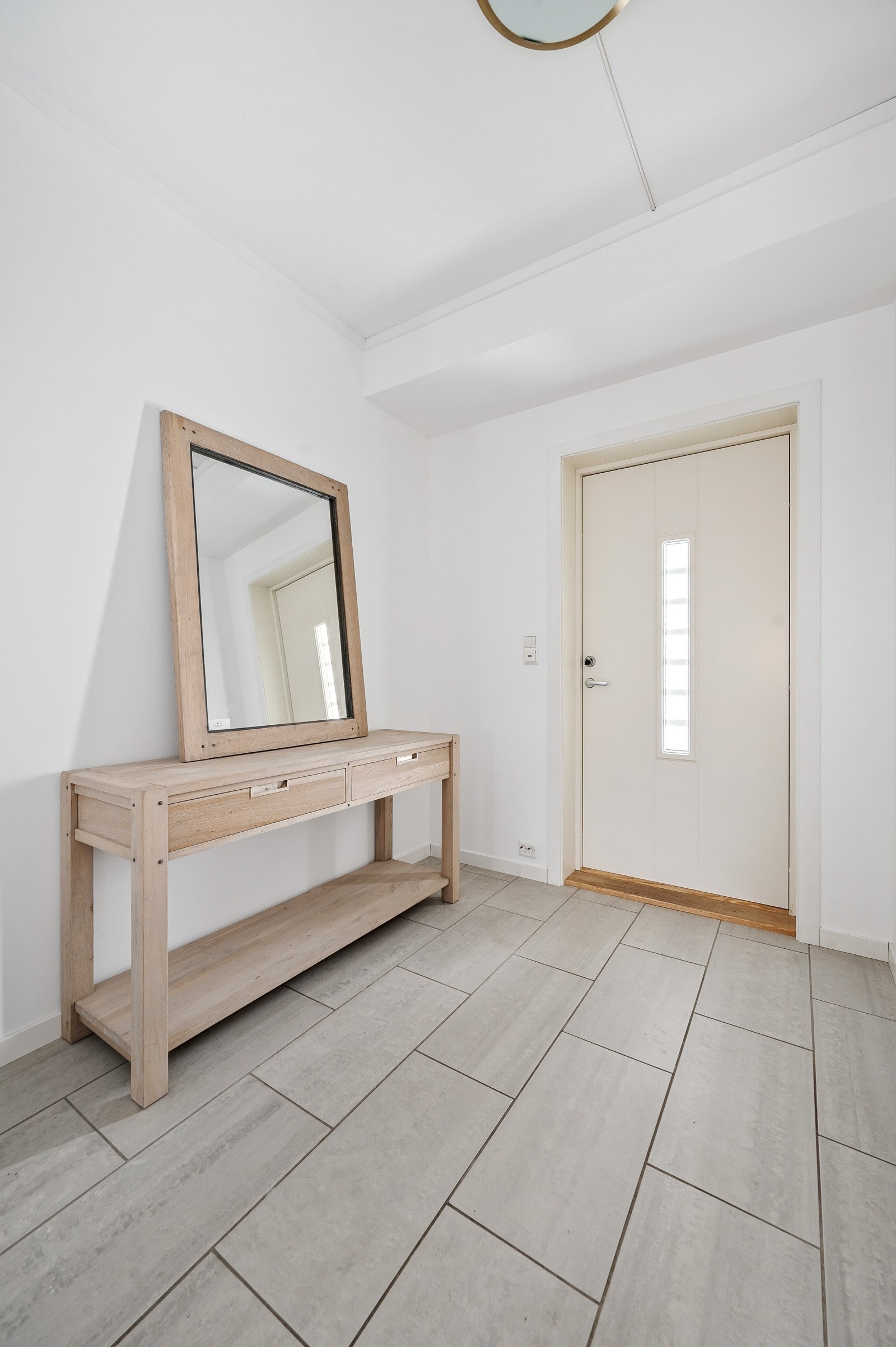 Romslig og lettstelt entrè med fliser på gulv og varmekabler. Galleribilde