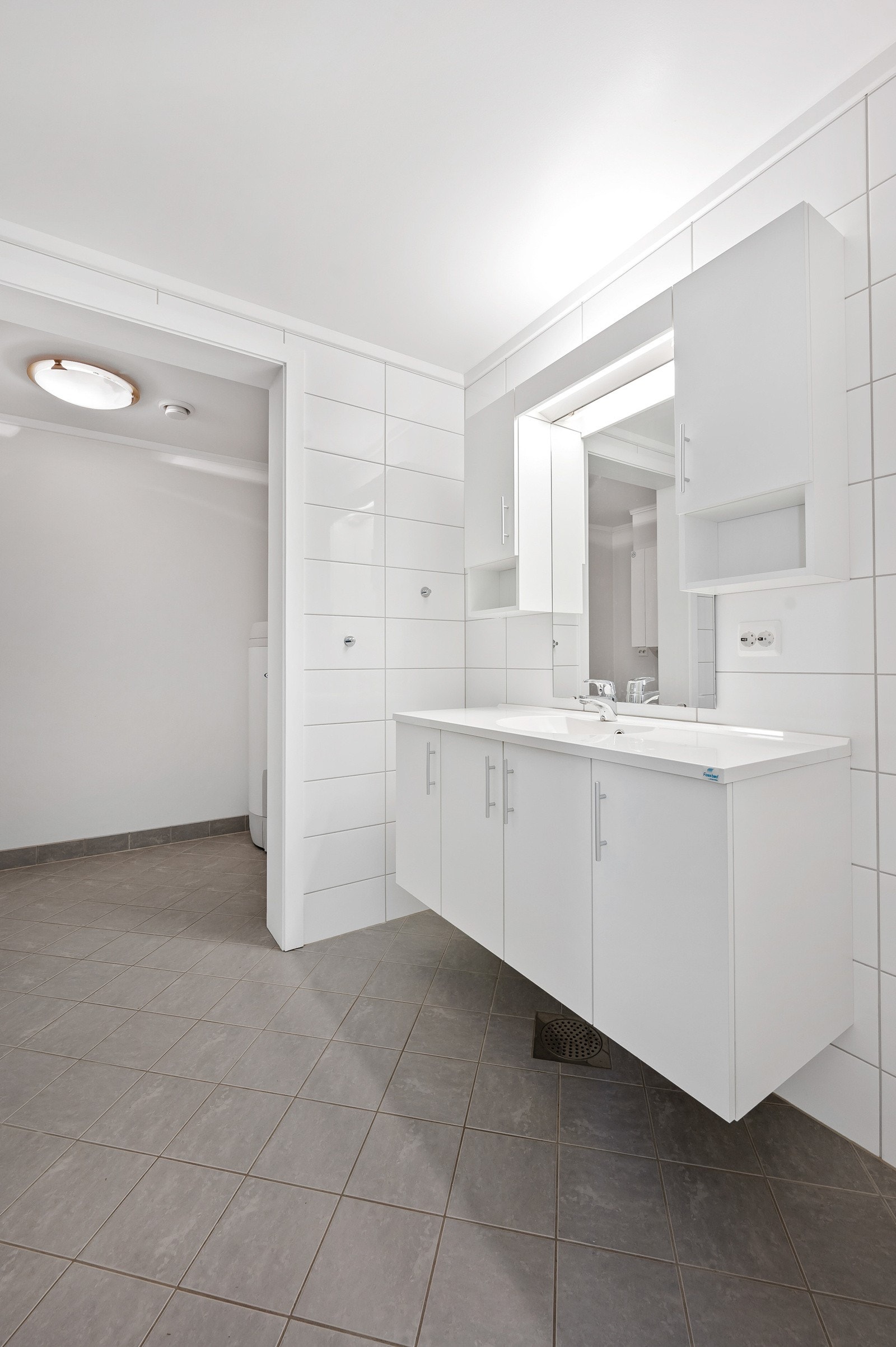 Dobbel innredning med enkel servant, sideskap og speil med overliggende lys Galleribilde