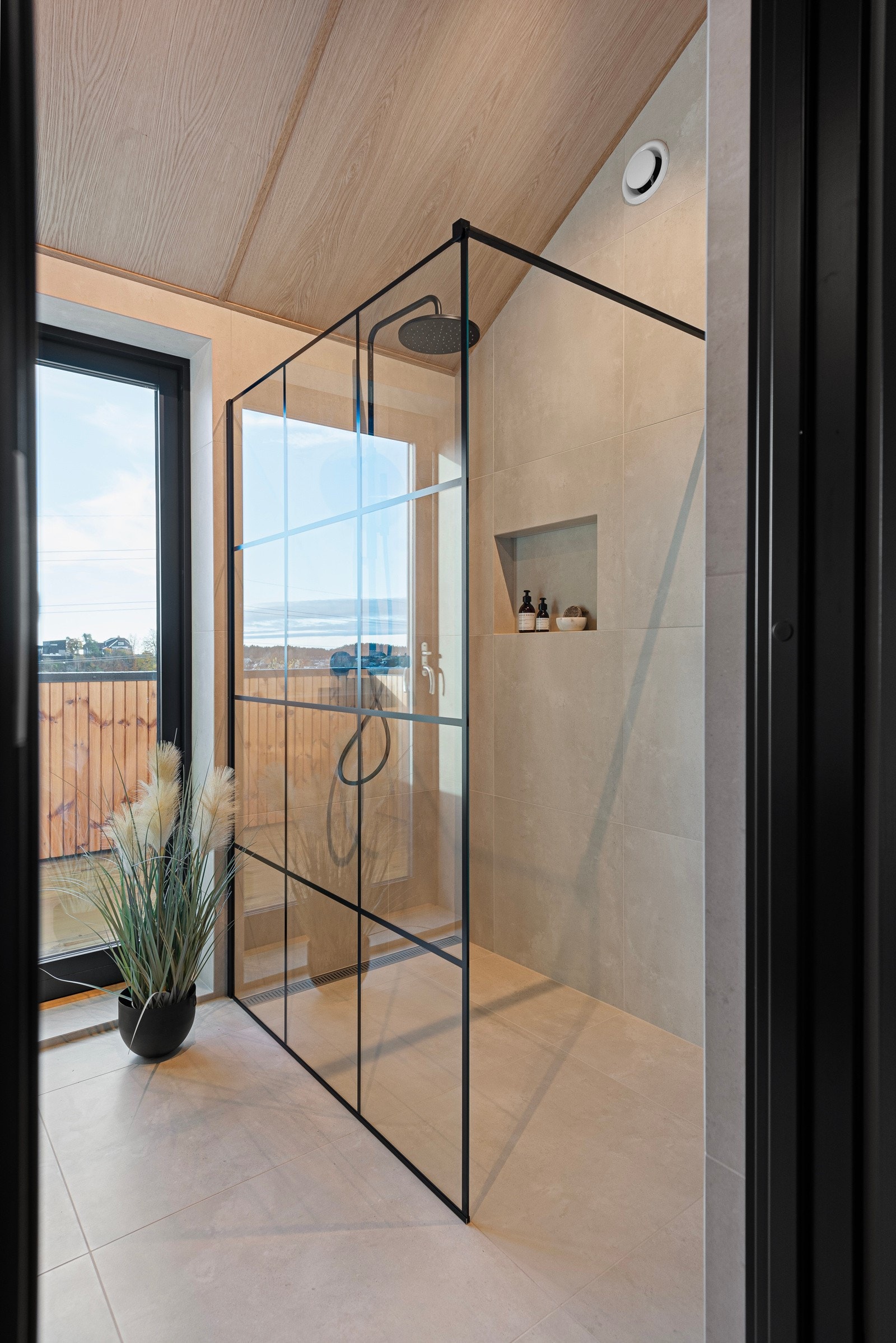 Badet har dusj med glassvegg og slukrenne, toalett og servantskap med innredning fra Kvik Galleribilde