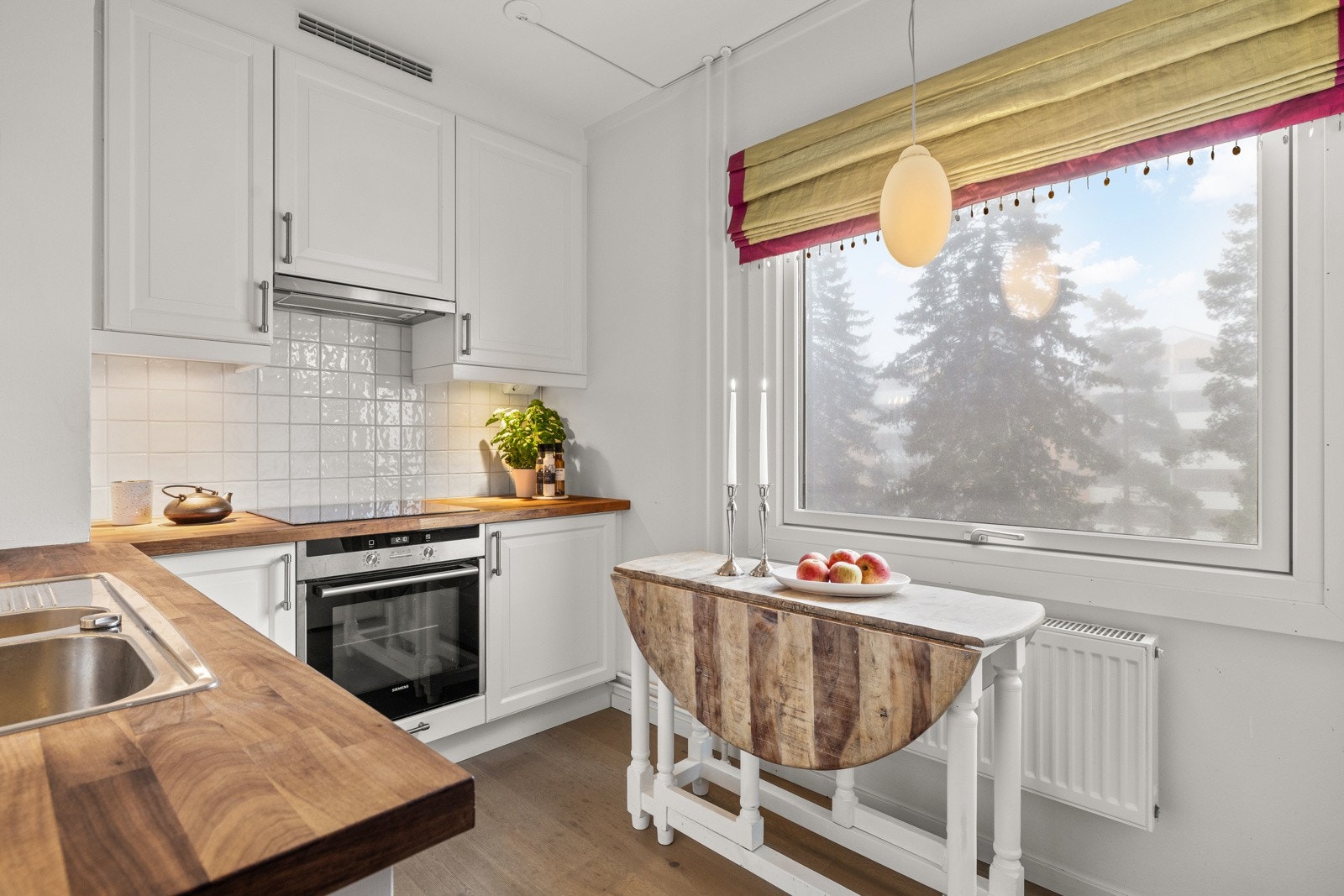 Fin kjøkkeninnredning med profilerte hvitmalte fronter. 1 vitrineskap med glasshyller. Benkeplater med topplag av valnøttfiner. Benkeplater er nylig oljet. Galleribilde